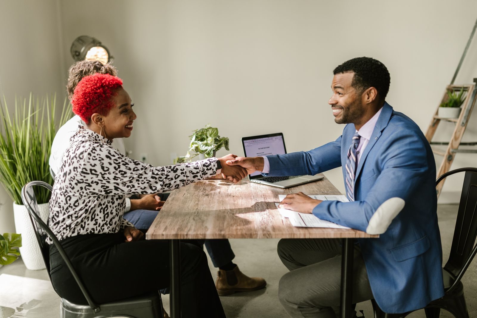 Business professionals shaking hands indoors with smiles, capturing a successful deal or agreement