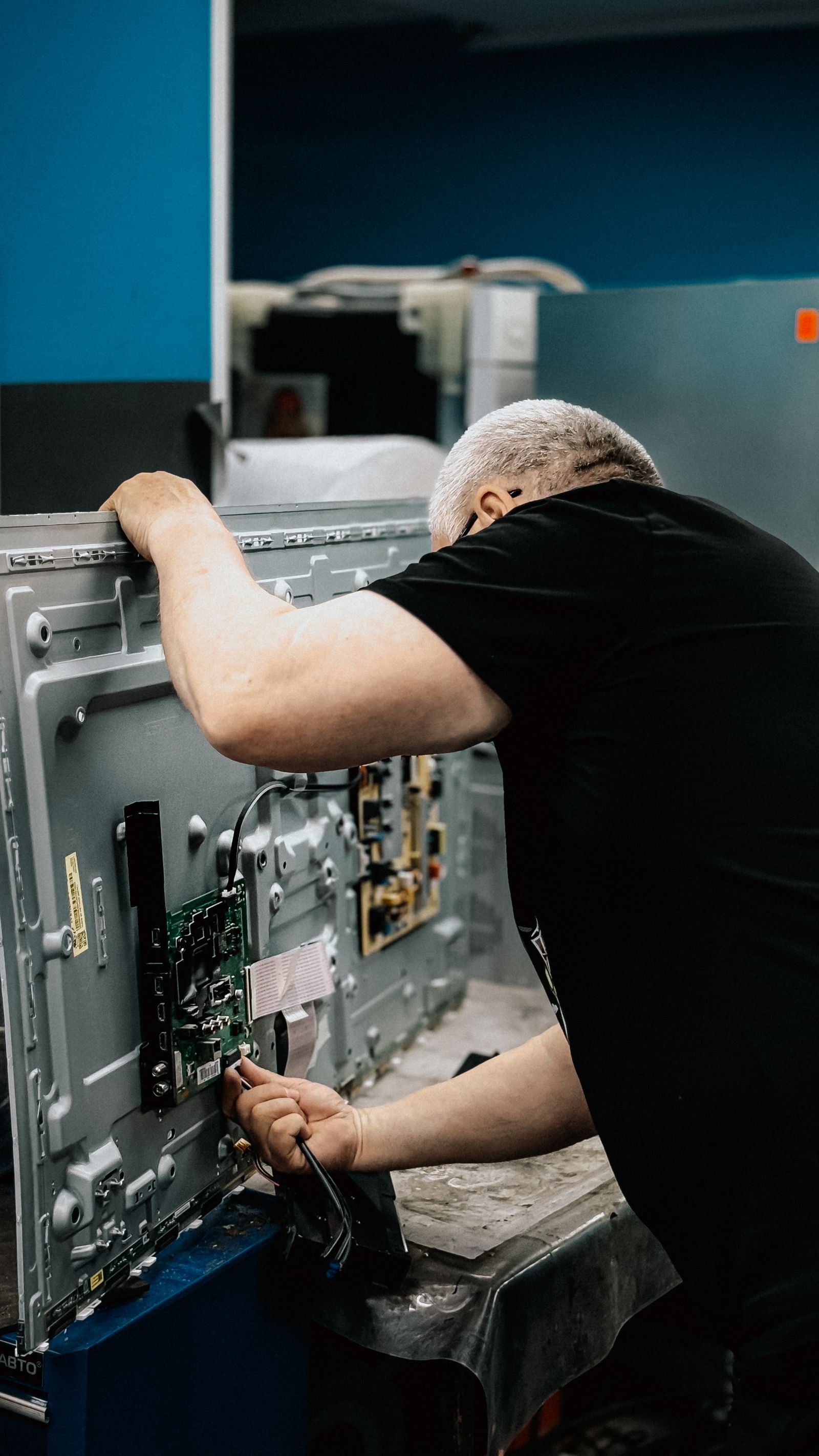 Technician repairing television circuit board indoors