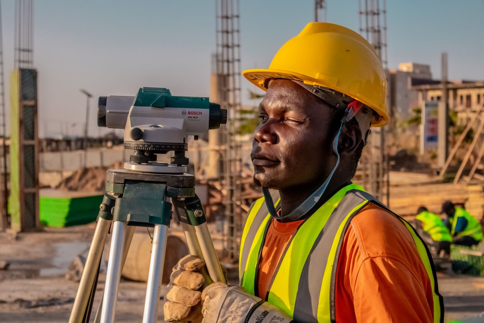 A construction worker using a theodolite for land surveying at a building site