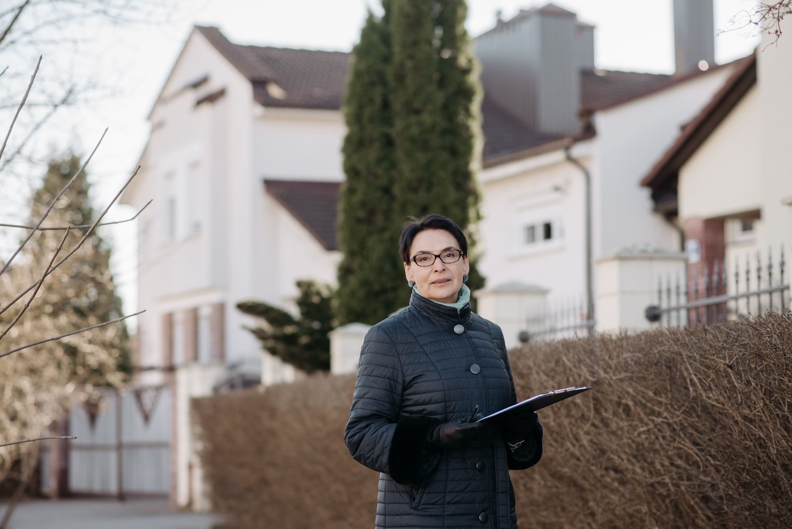 Adult woman in eyeglasses standing outside holding a clipboard, ideal for business or lifestyle themes