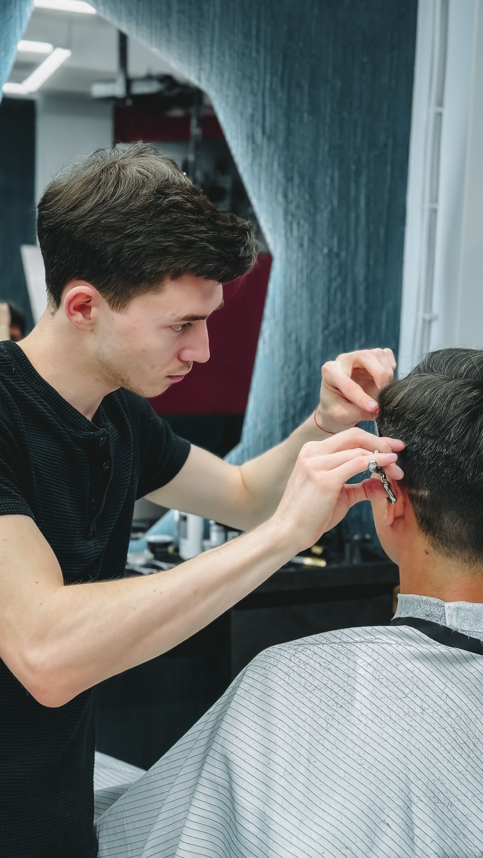 Barber giving client a haircut in modern salon