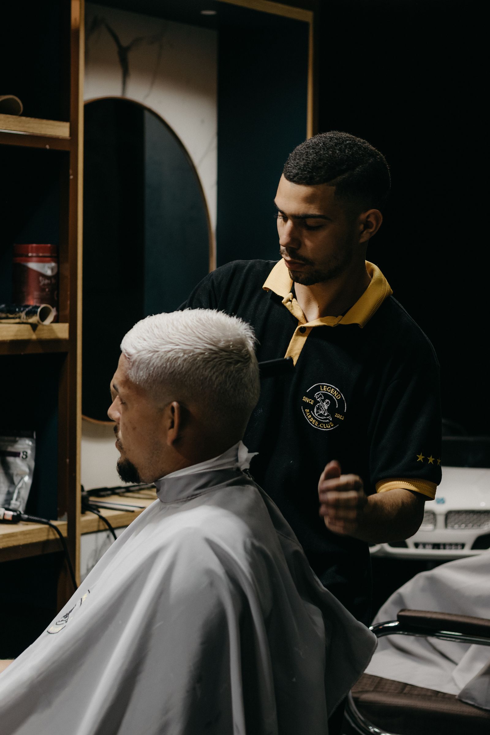 Barber in hair salon standing by client on chari
