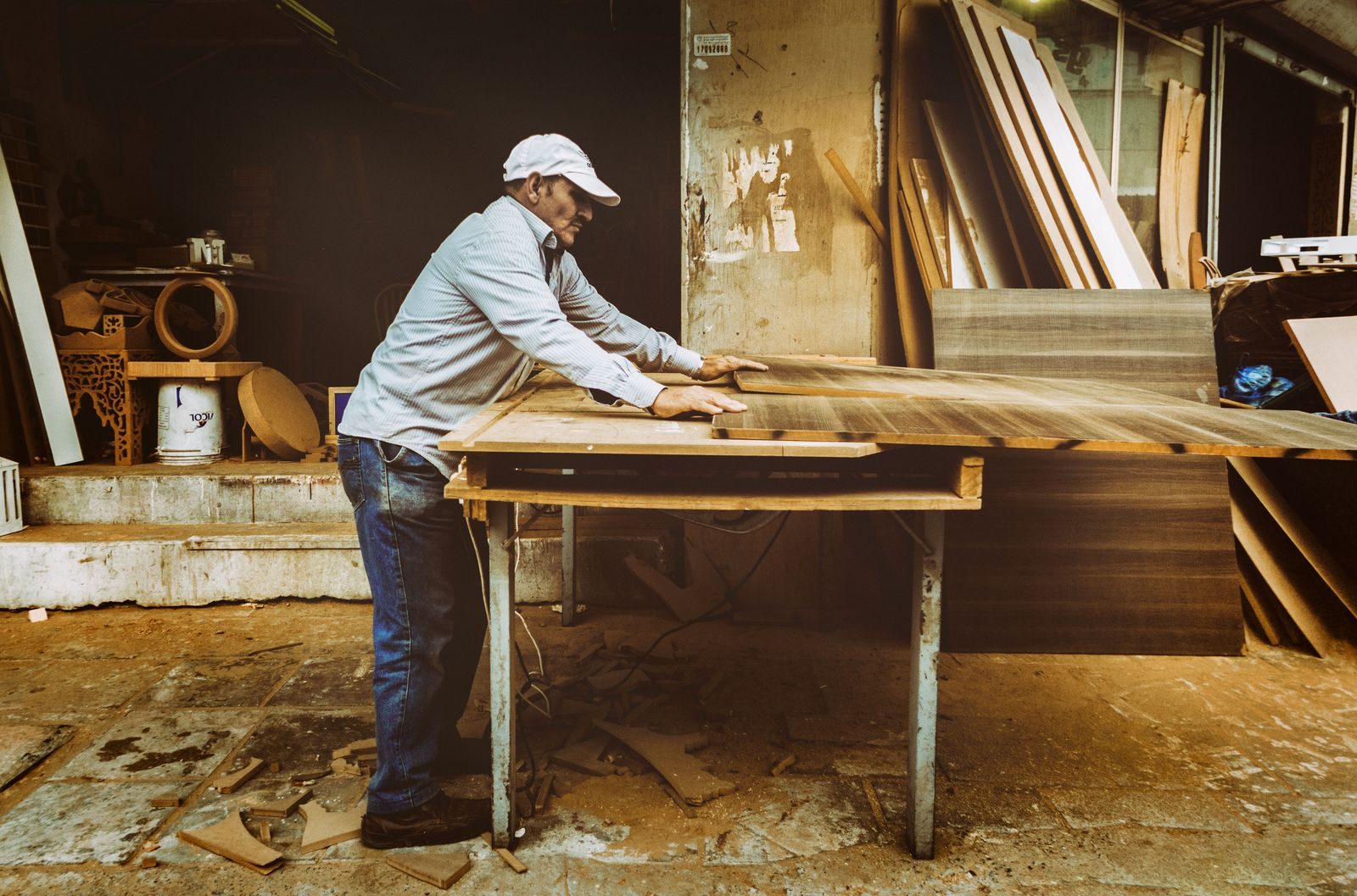 Carpenter focuses on woodworking project inside a busy workshop, surrounded by materials