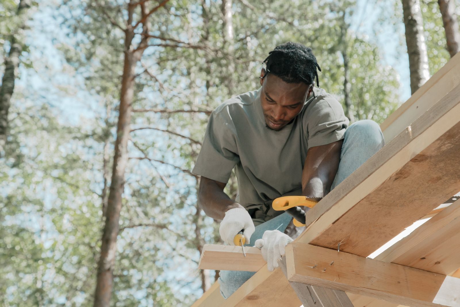 Skilled carpenter focused on building a wooden structure outdoors on a sunny day