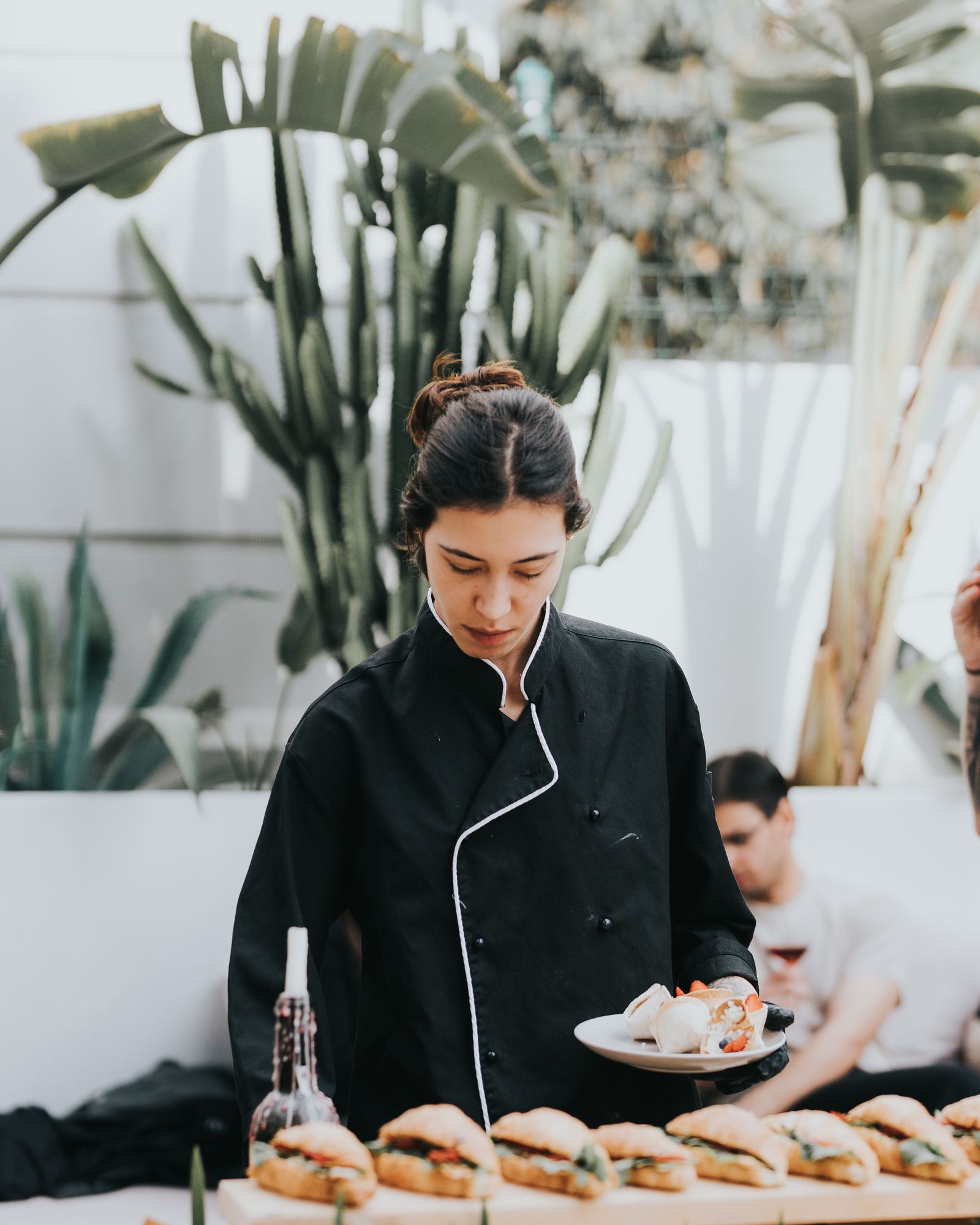 Woman standing by table with croissant sandwiches