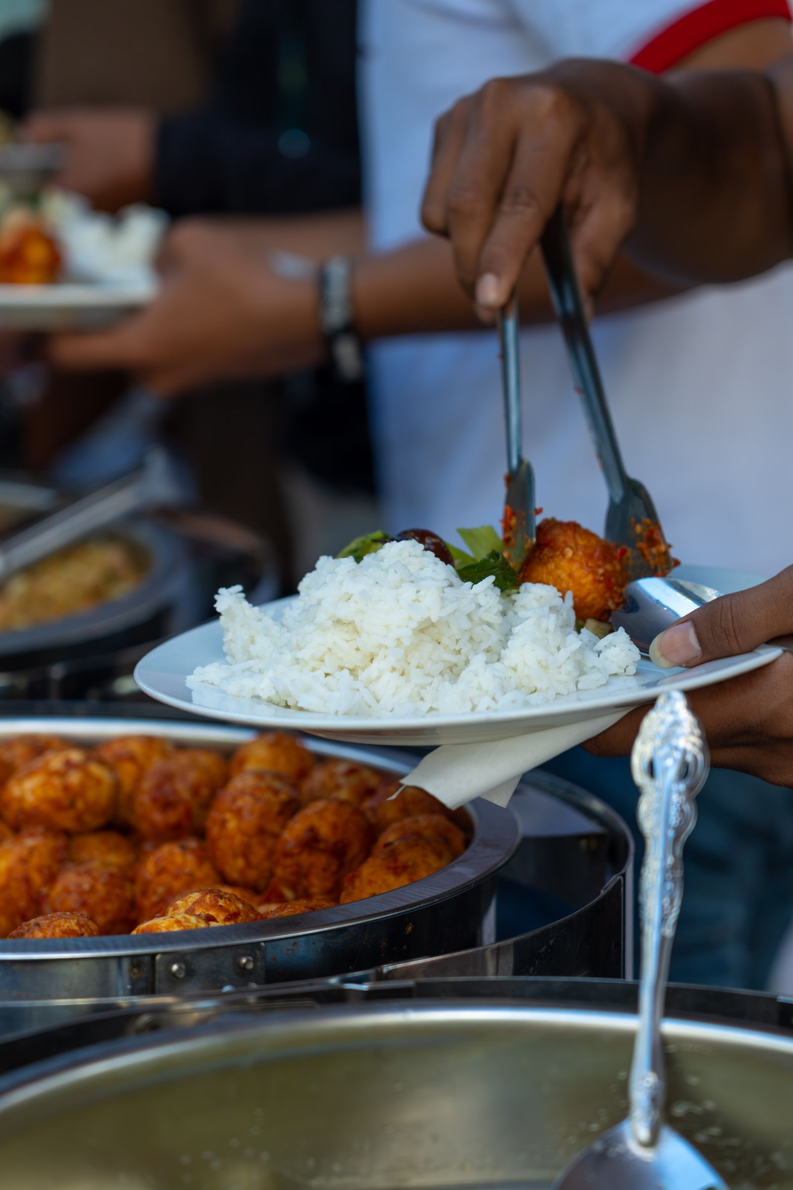 Buffet plate with rice and meatballs being served