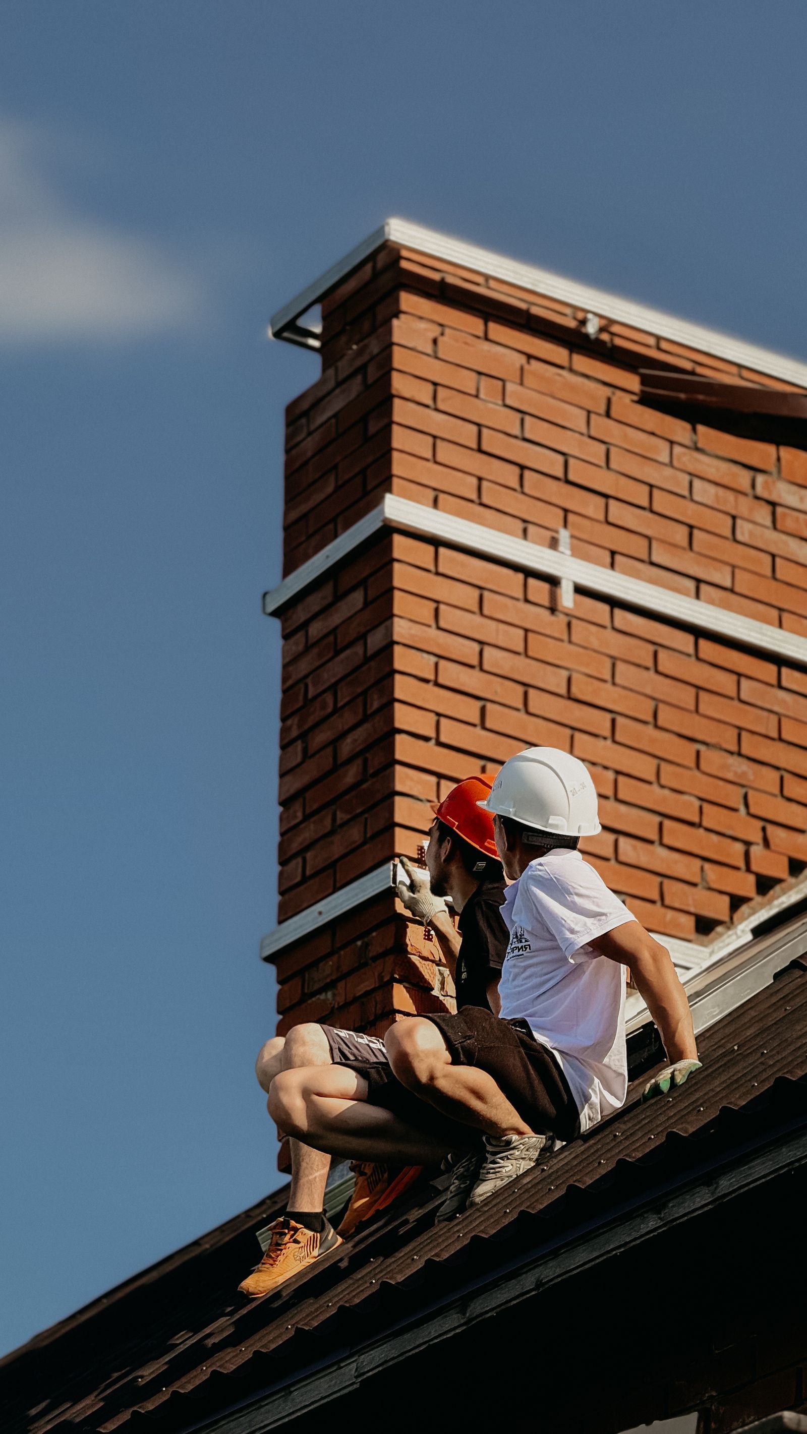 Construction workers repairing chimney on rooftop