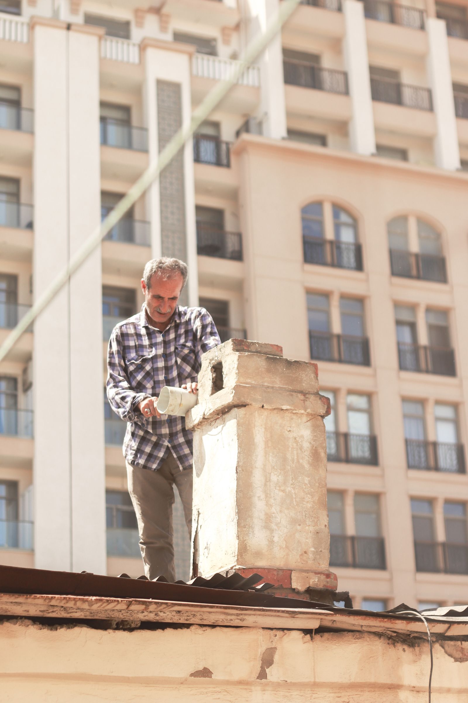 Man in shirt working on roof