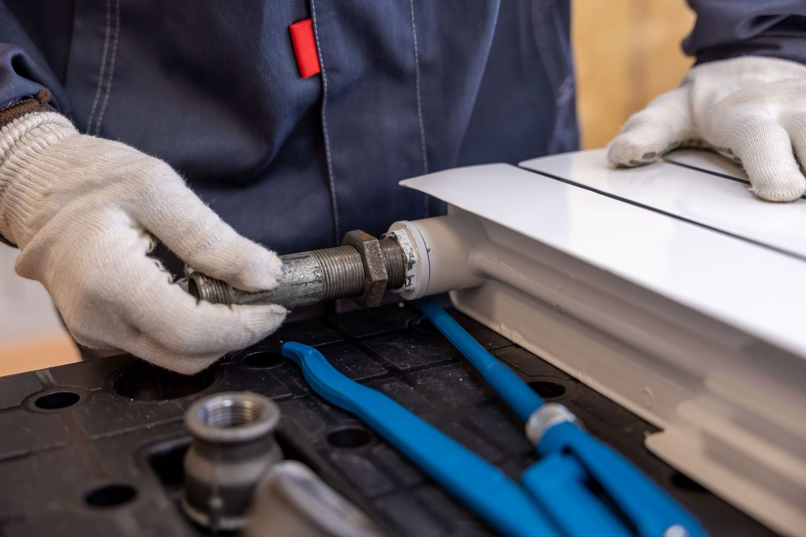 Close-up of a plumber installing a radiator pipe using specialized tools