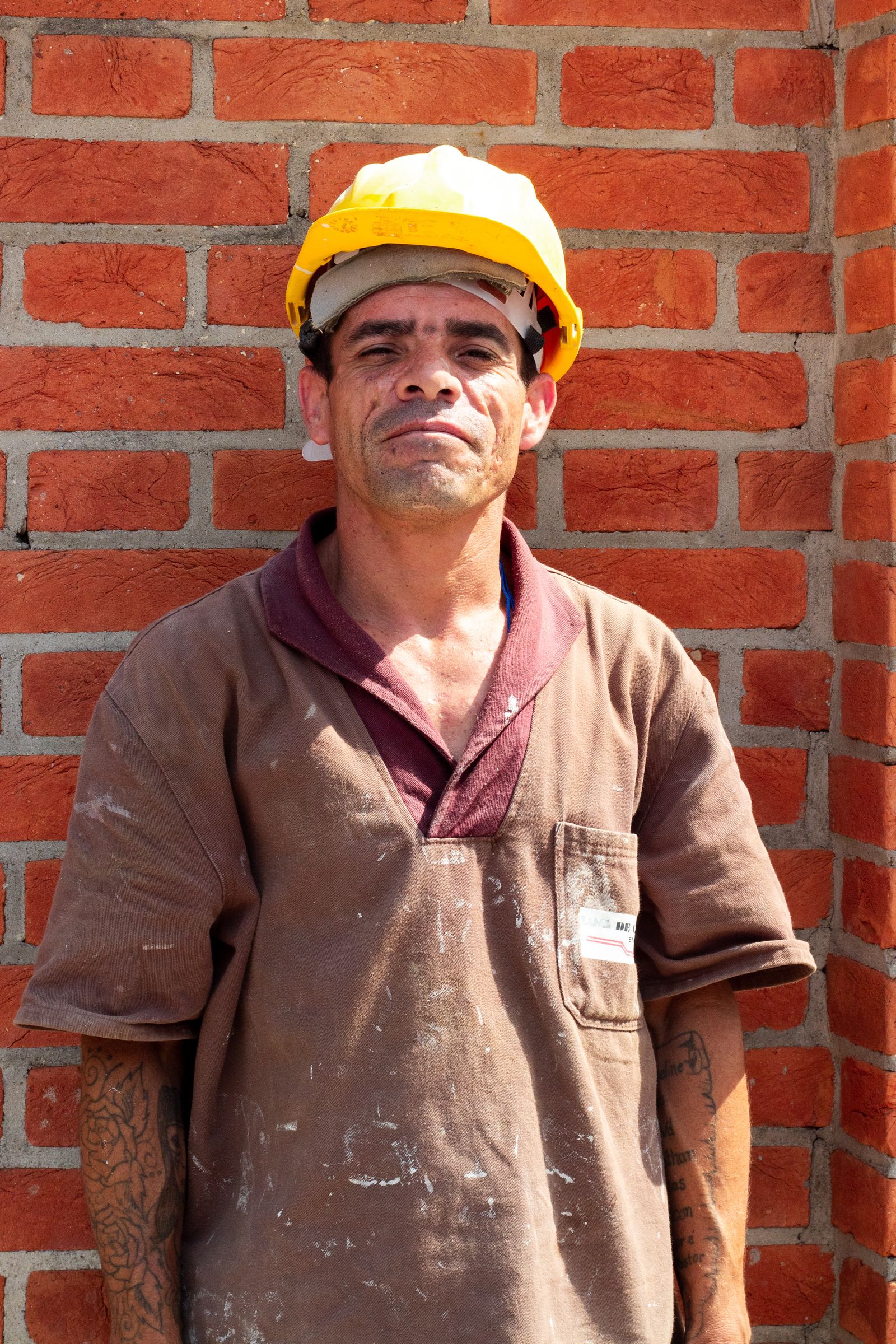 Construction worker in front of brick wall in sunlight