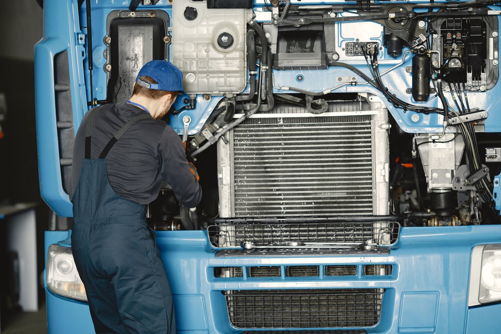 Mechanic in uniform working on a truck engine in an industrial workshop. Perfect for automotive maintenance th