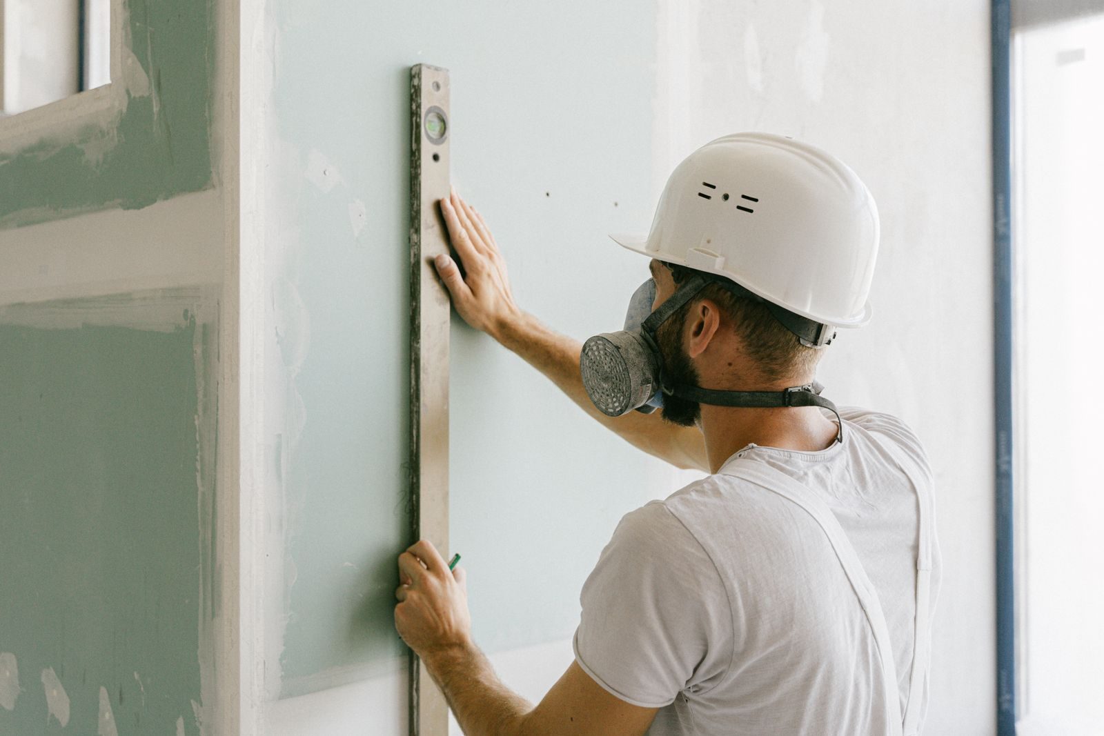 A construction worker using a leveler to ensure wall accuracy, showcasing precision