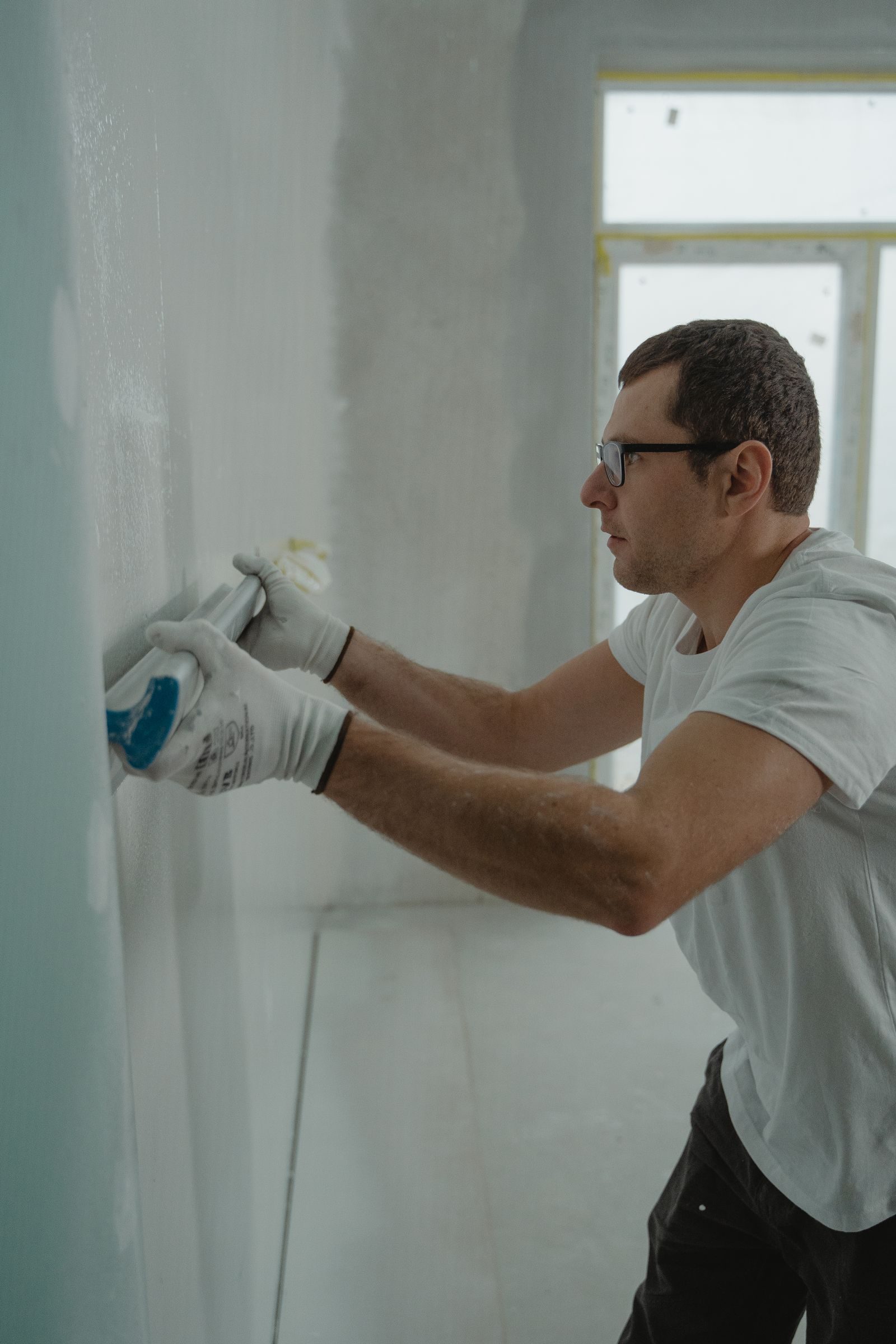 A focused worker applying drywall compound during a home renovation project indoors