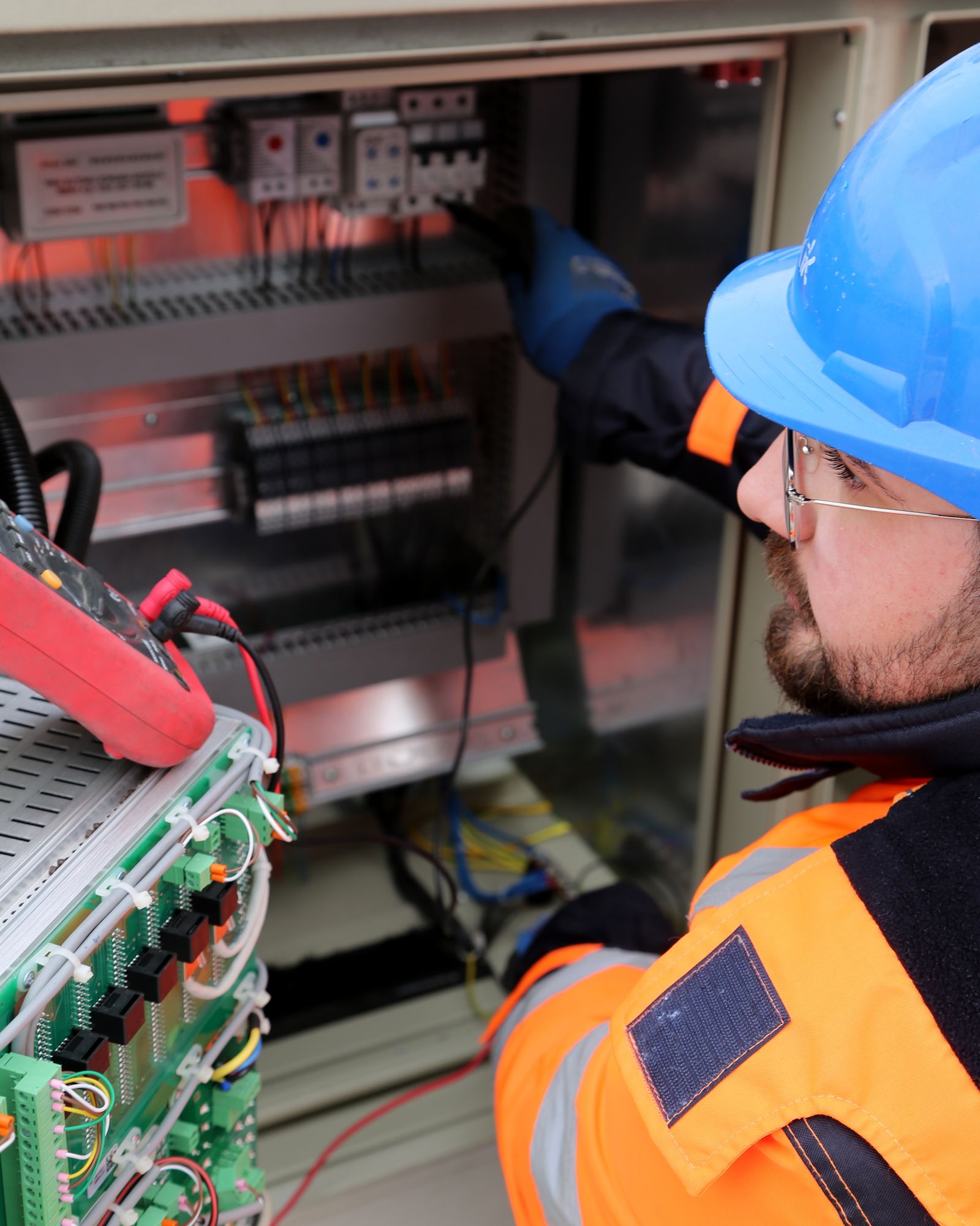 Man in hard hat and eyeglasses working with electric equipment
