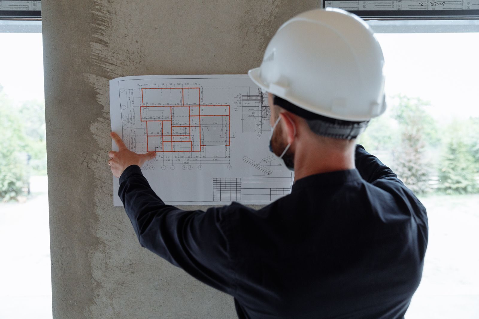 Engineer in hardhat reviewing architectural floor plans at construction site