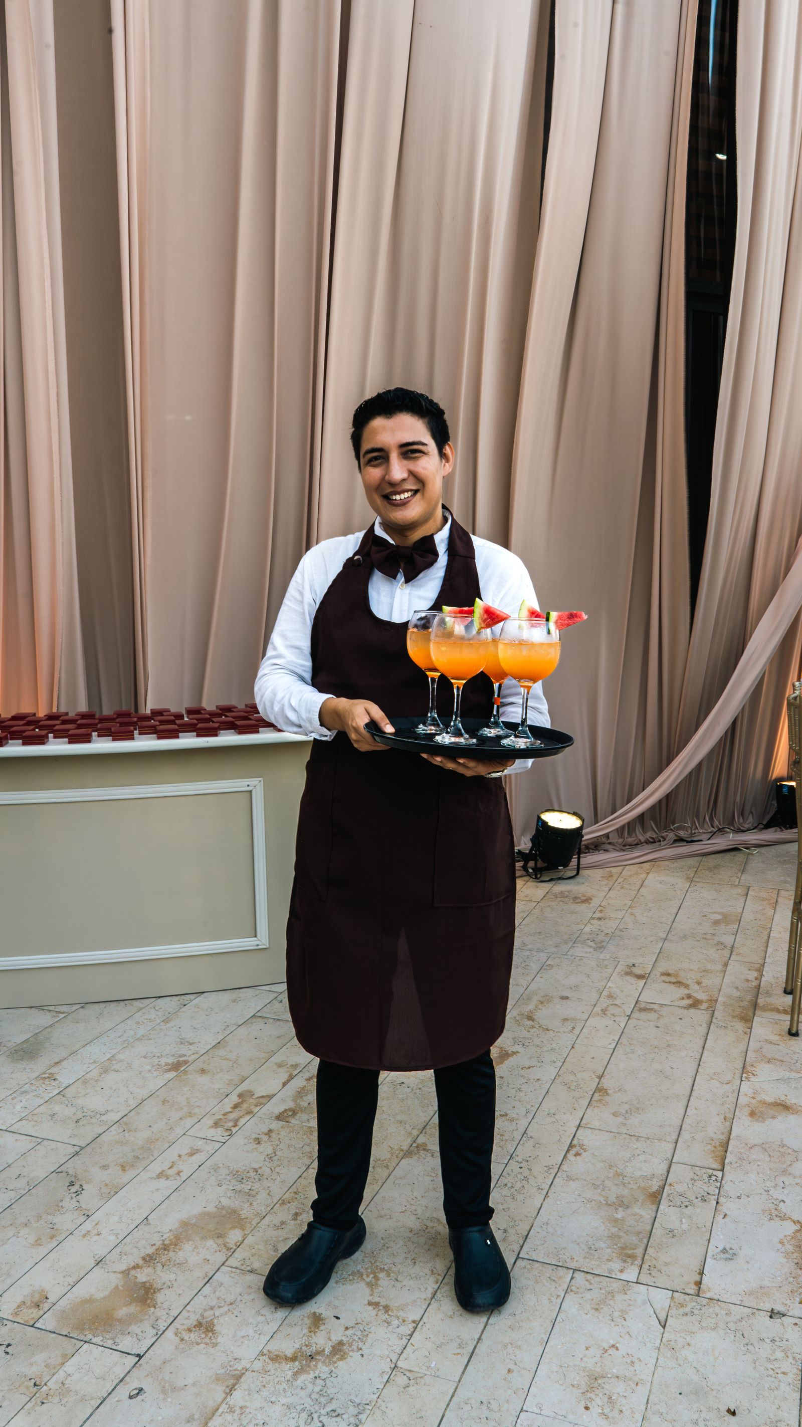 Smiling waiter serving colorful cocktails at event