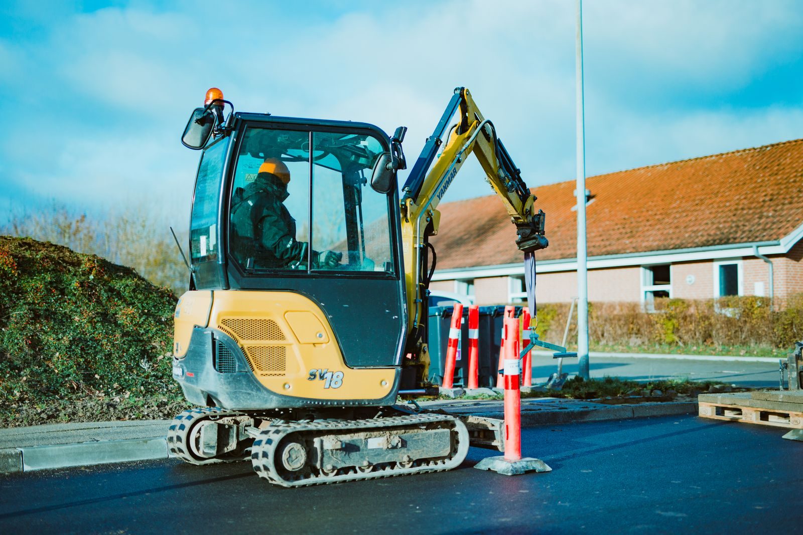 A mini excavator operating on a construction site in Odder, Denmark. A person is seen working