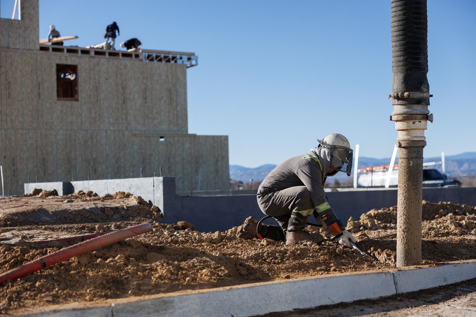 Construction worker operates machinery at a building site in Colorado under a clear blue sky