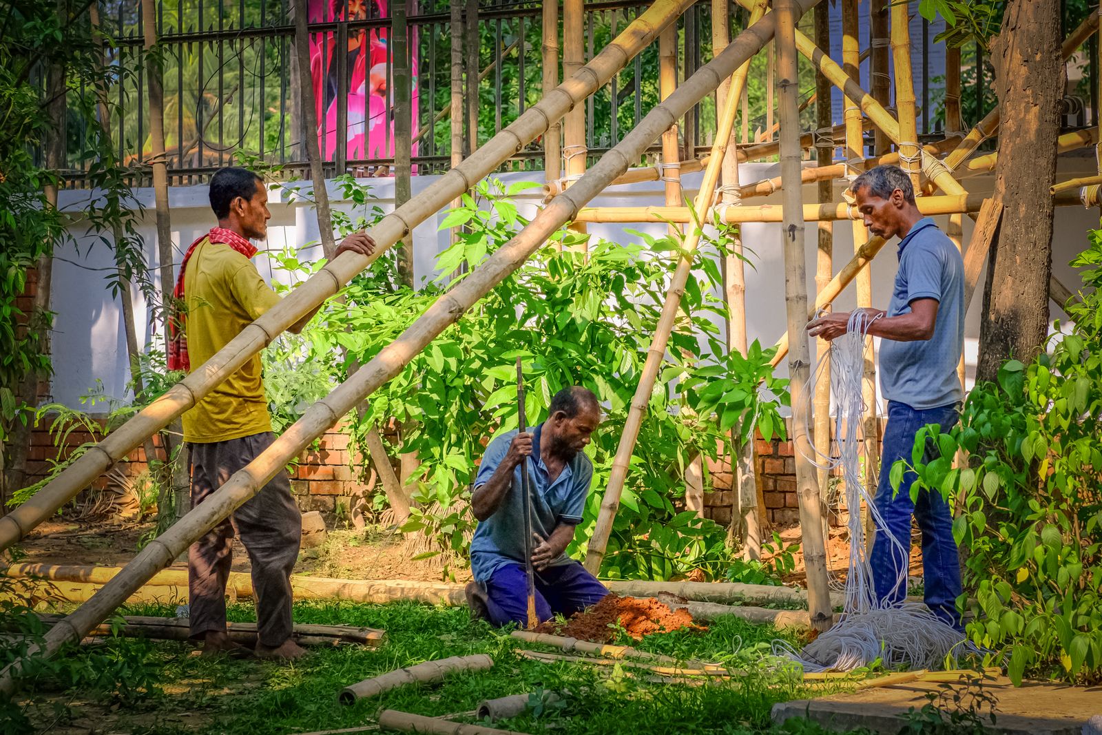 Workers constructing bamboo structure outdoors
