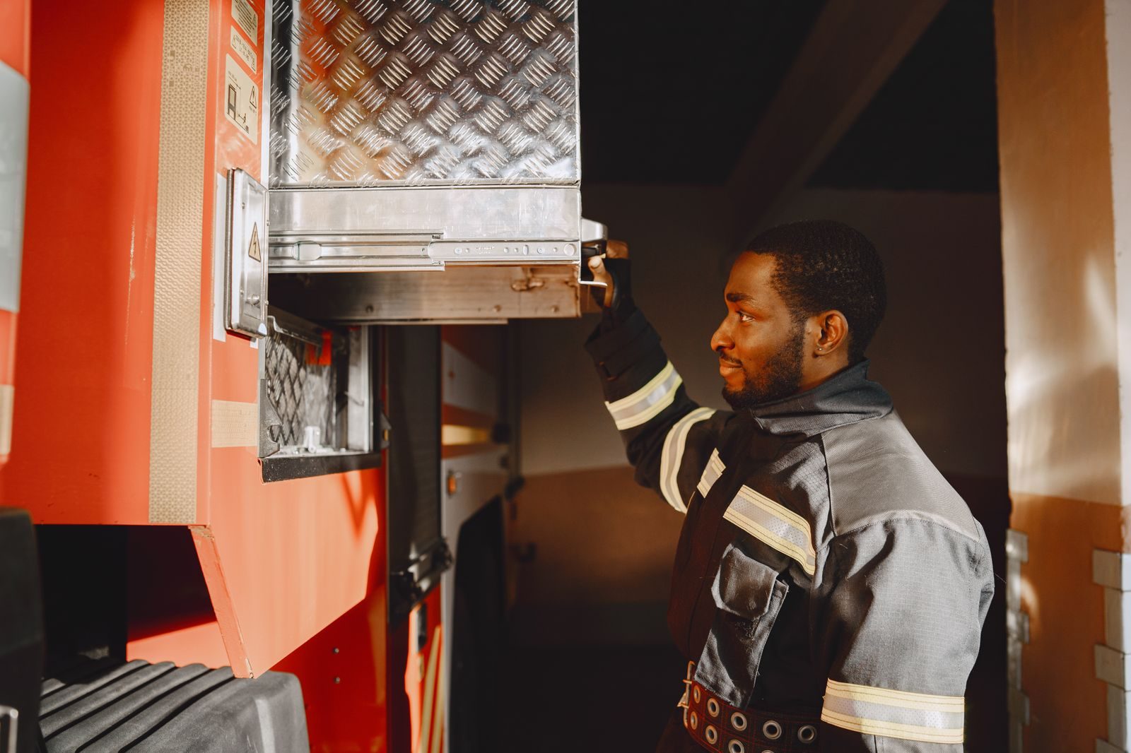 Close-up of a firefighter in uniform working with equipment on a fire truck