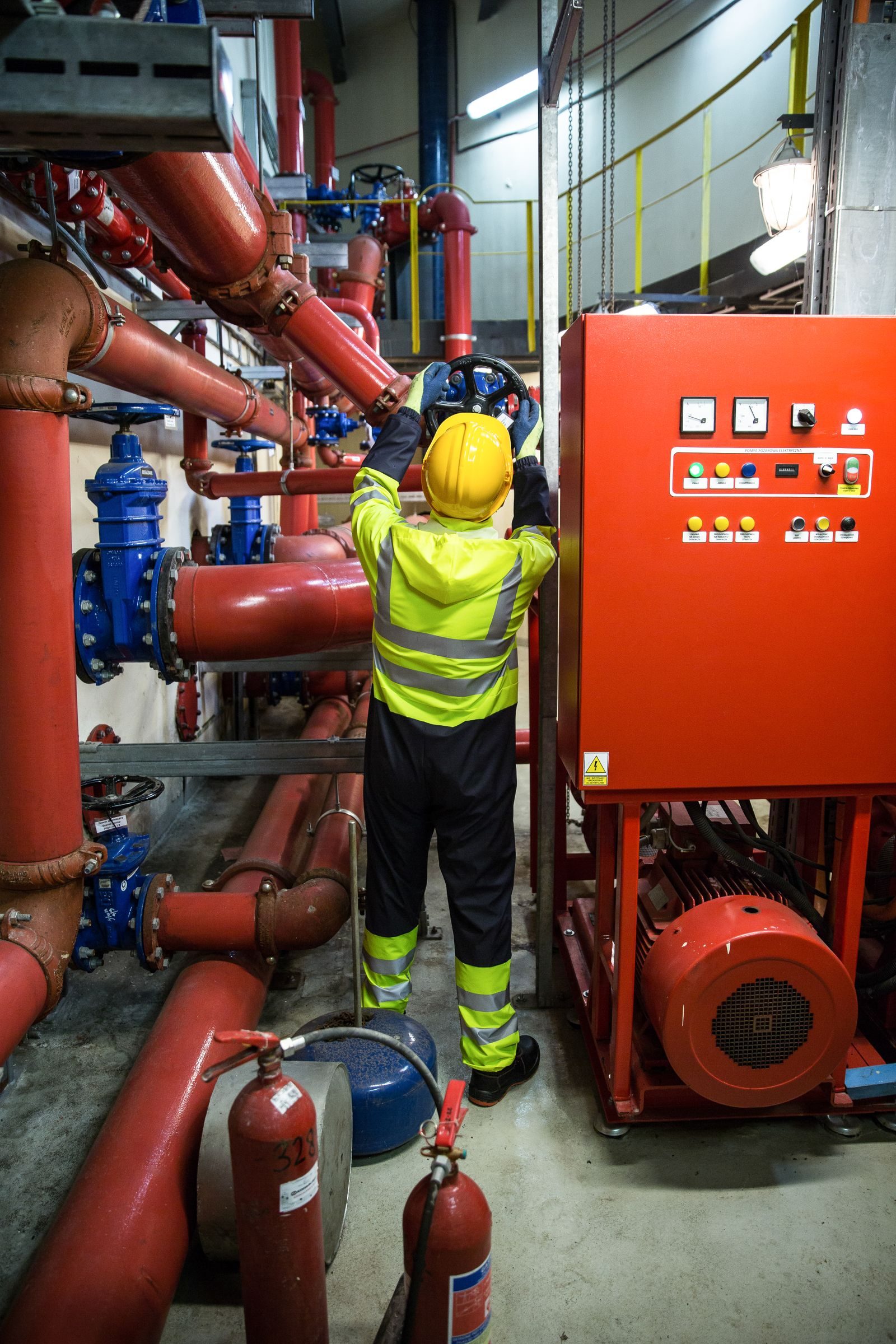 Worker in uniform operates machinery in industrial setting, emphasizing safety and productivity