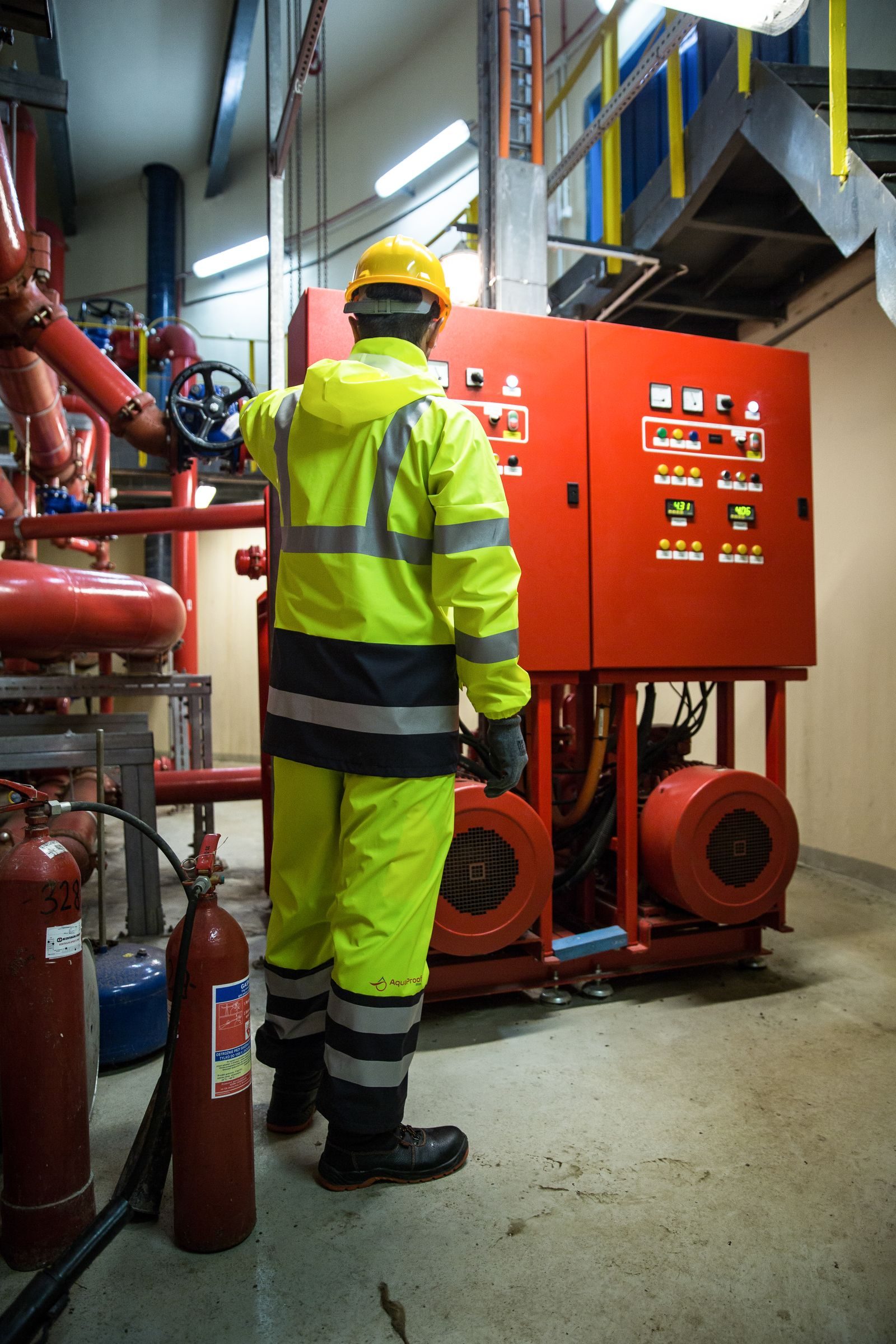 Engineer in high-visibility uniform operates control panel in industrial setting