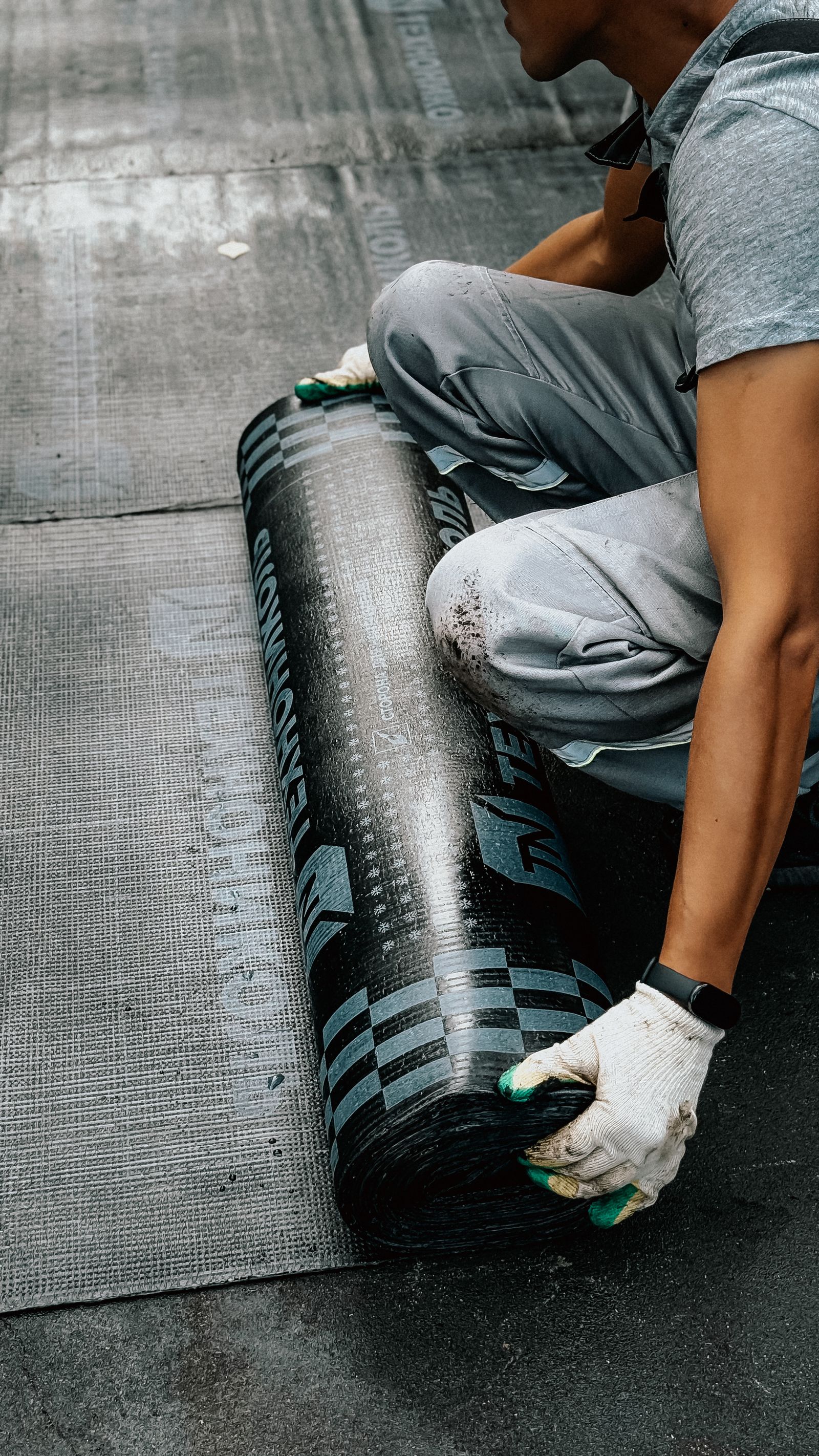 Worker installing waterproof membrane on roof