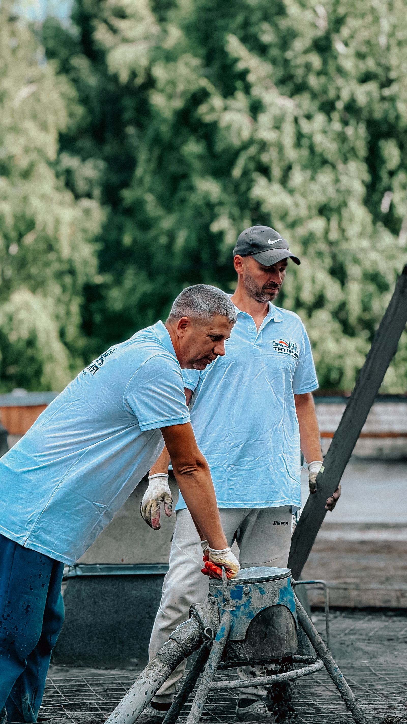 Two construction workers pouring concrete outdoors