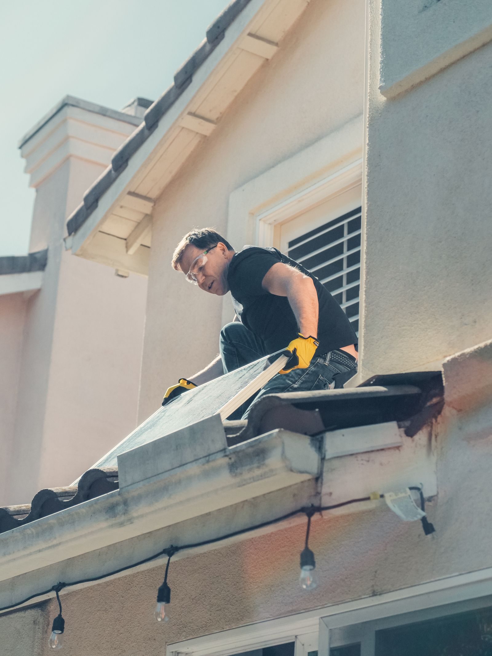 A worker is installing solar panels on a residential rooftop, promoting clean energy