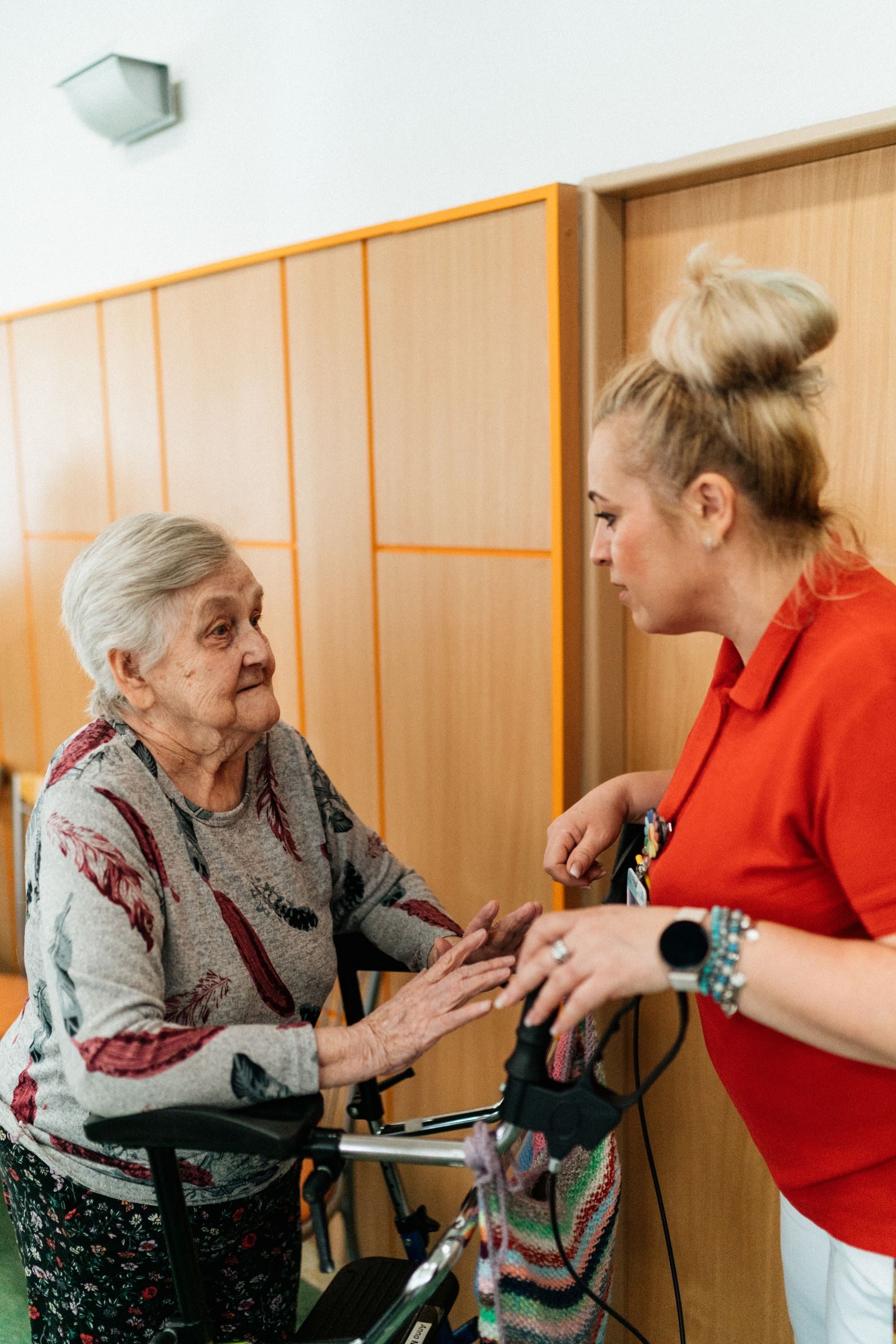 A caregiver assists an elderly woman in a retirement home corridor, fostering companionship and support