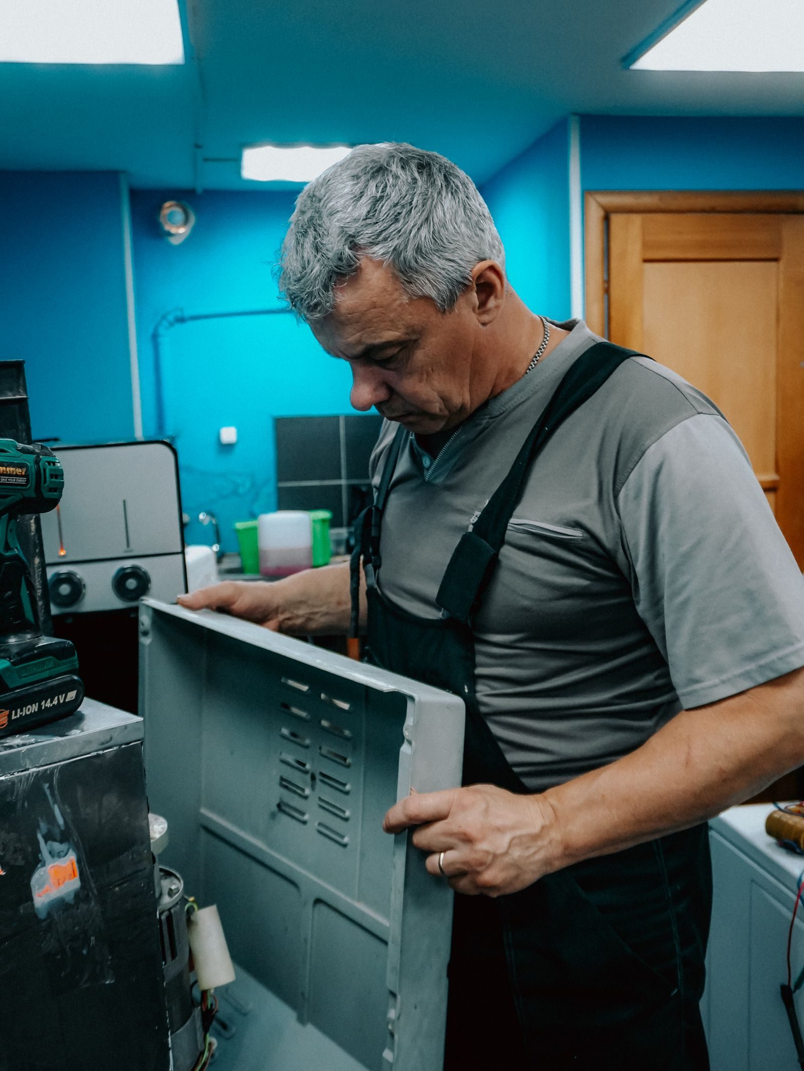 Repair technician examines appliance indoors, showcasing focus and skill