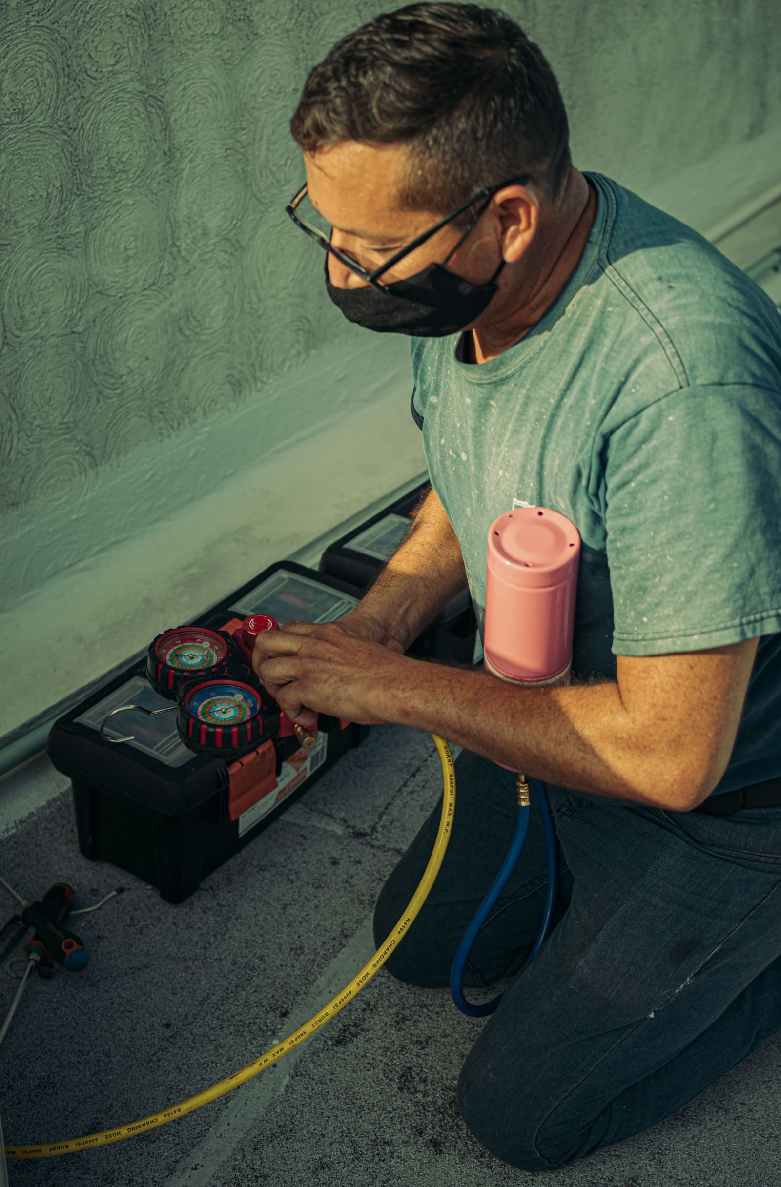 A technician kneels outdoors, performing HVAC maintenance using specialized tools, enhancing system performanc