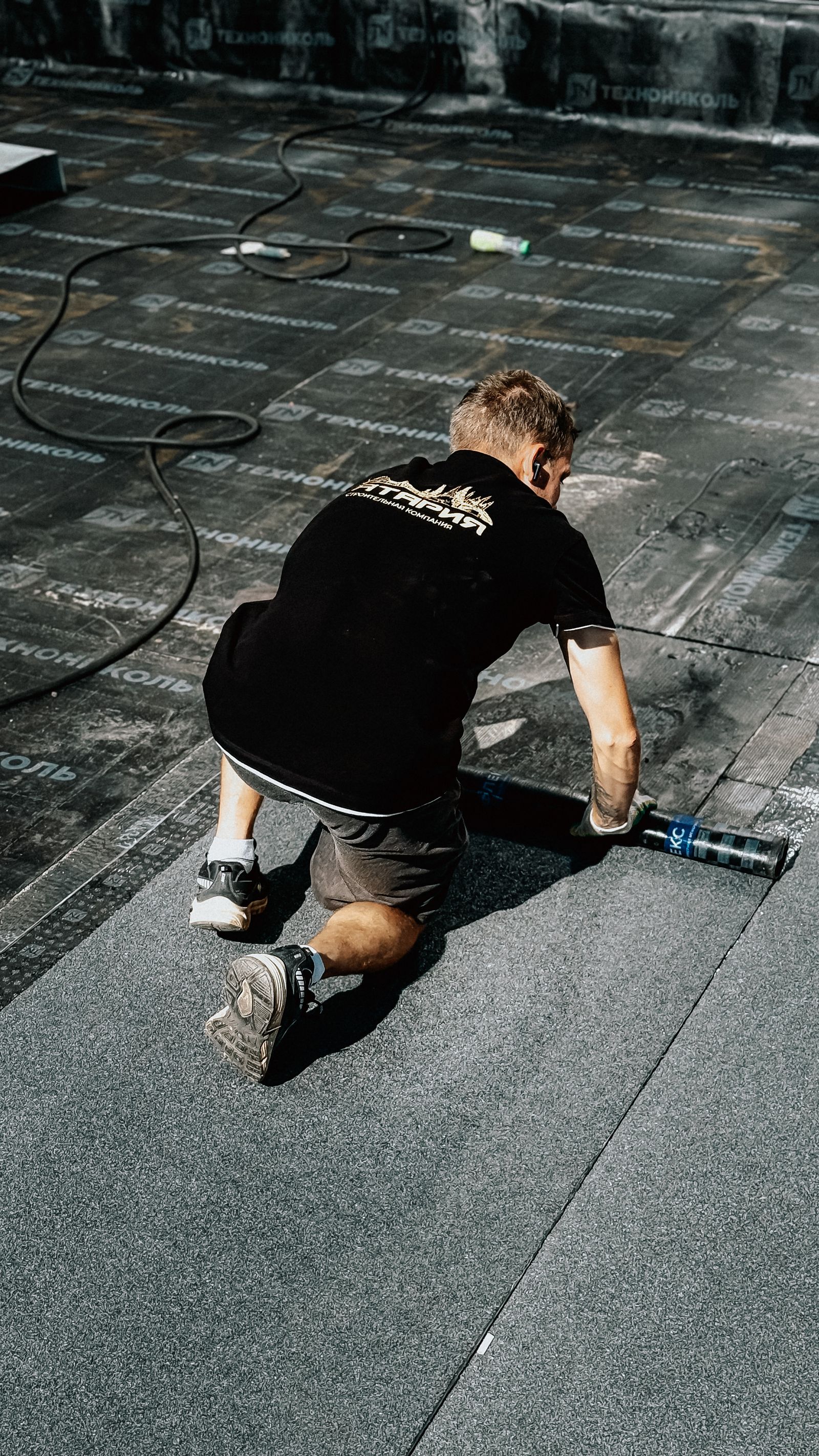 Worker applying roofing material on construction site