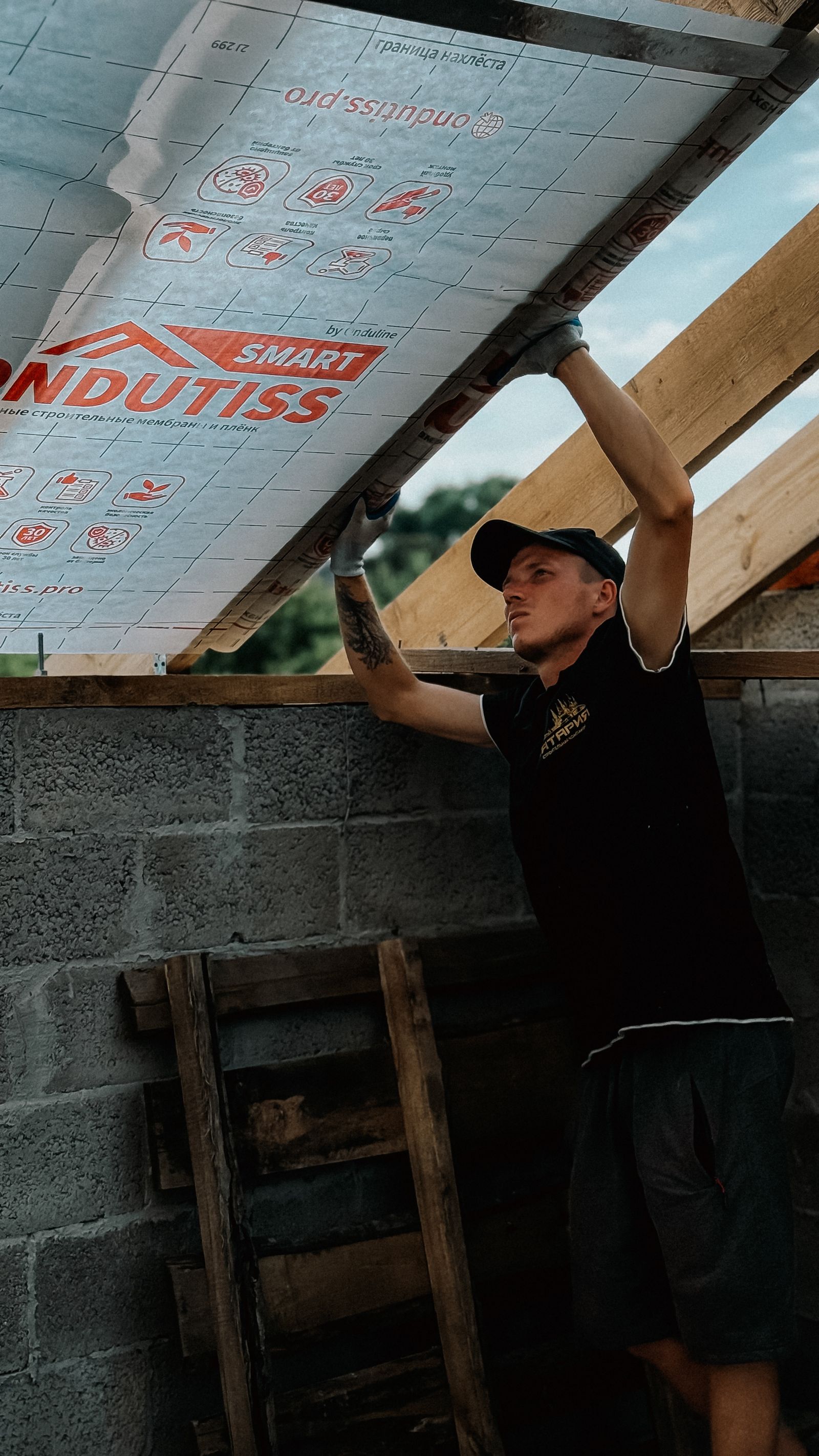 Worker installing roof insulation in unfinished building