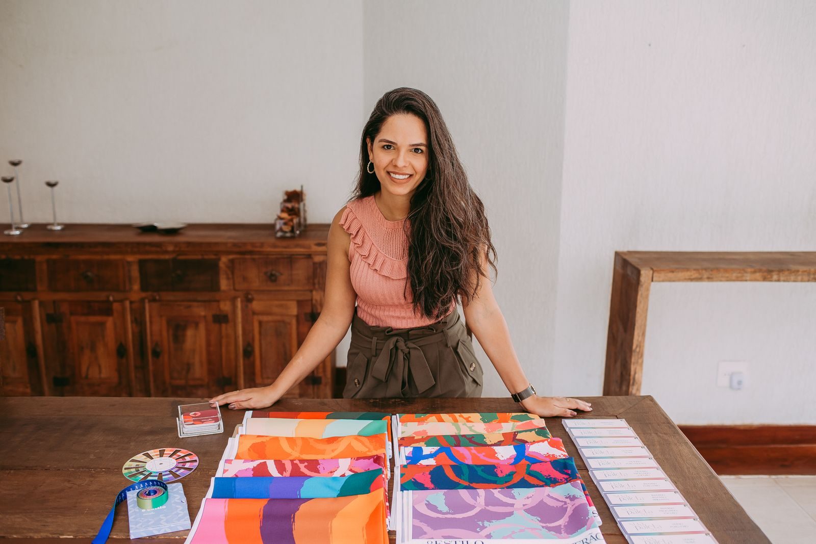 Smiling young fashion designer presenting colorful fabric samples in a modern studio