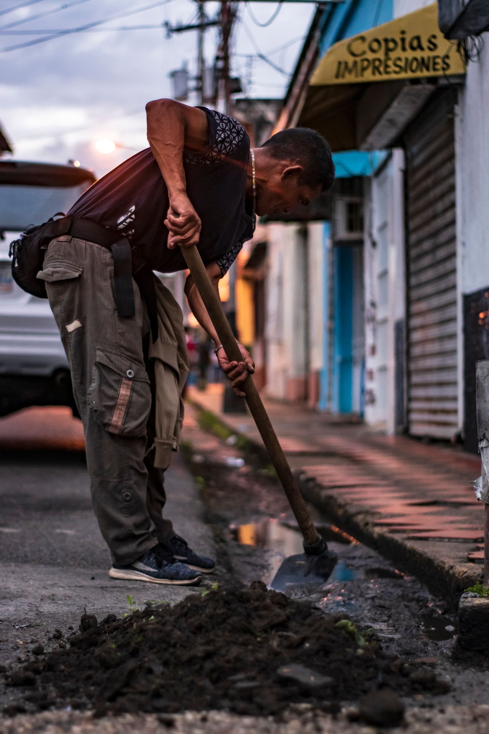 A man repairing city street with a shovel during dusk, showcasing urban life and hard work