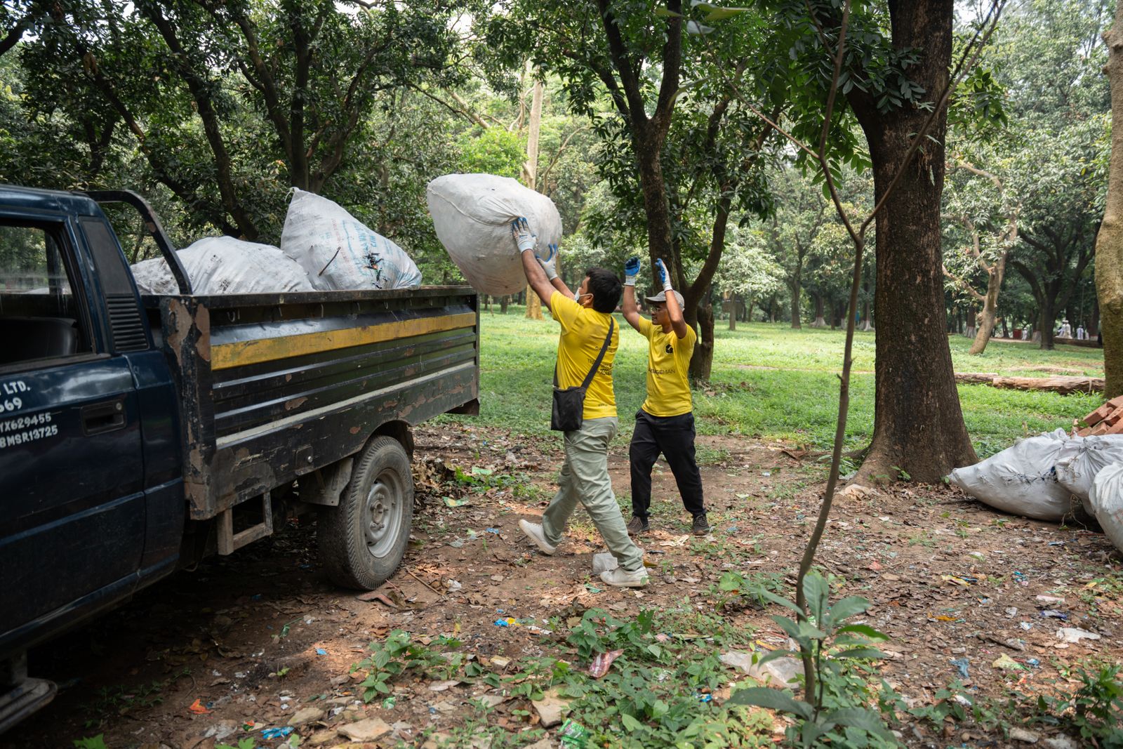 Workers loading truck with garbage bags in park