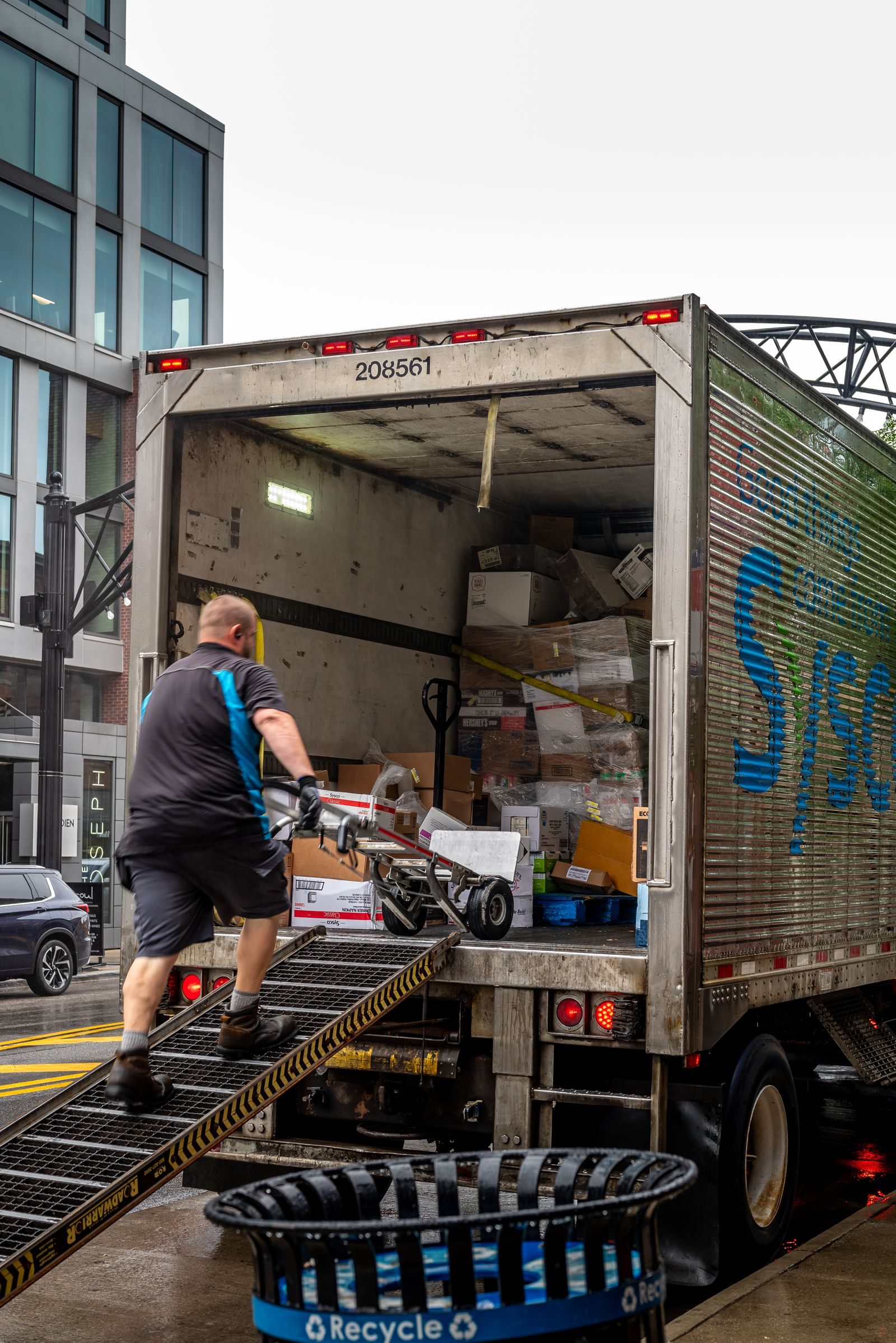 A man loads packages into a delivery truck in a modern urban area