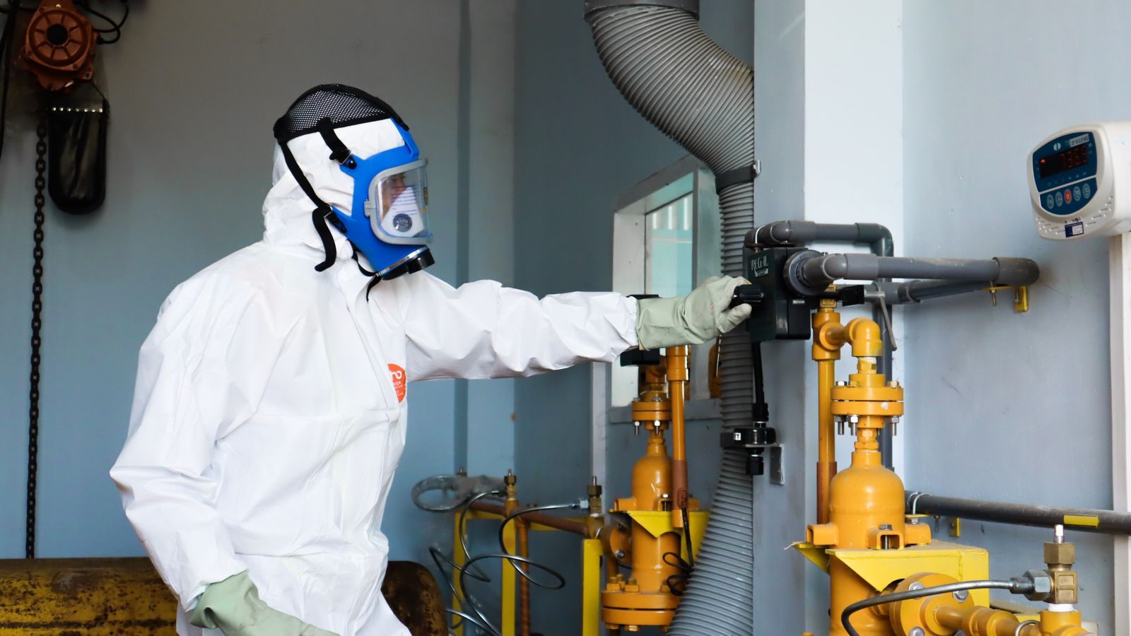 Industrial worker in protective gear inspecting machinery for safety compliance in Indonesia