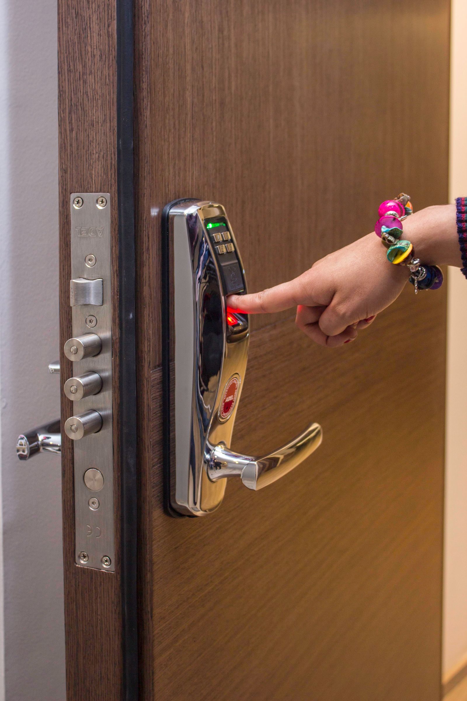 A hand using fingerprint access on a digital security door lock, enhancing safety