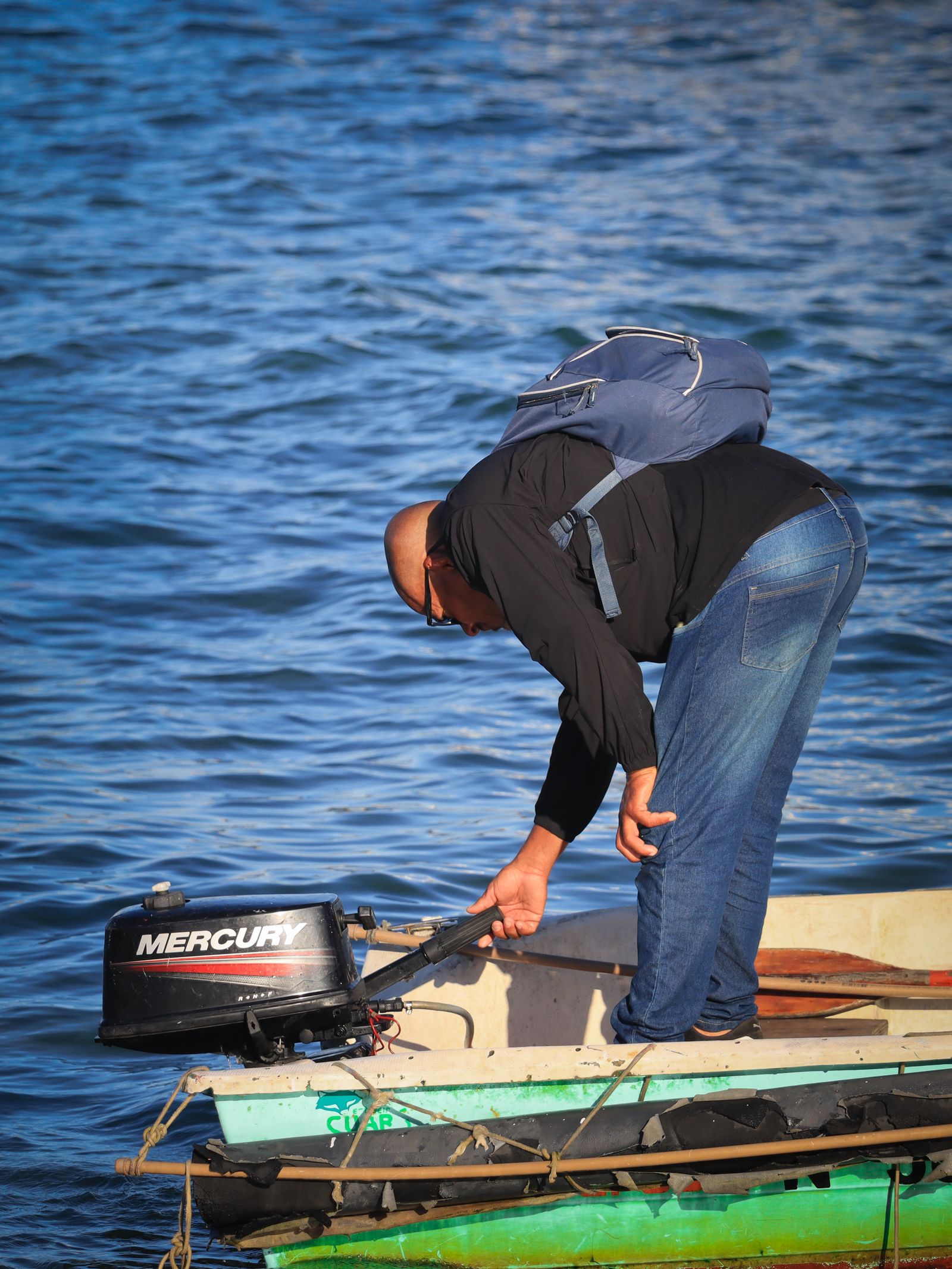 Man operating boat motor on calm waters