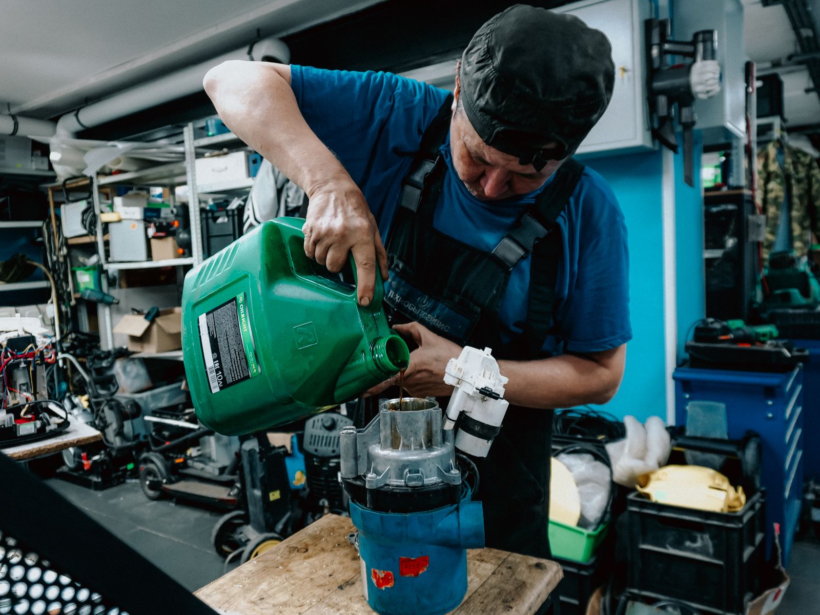 Mechanic pouring oil into engine part in workshop