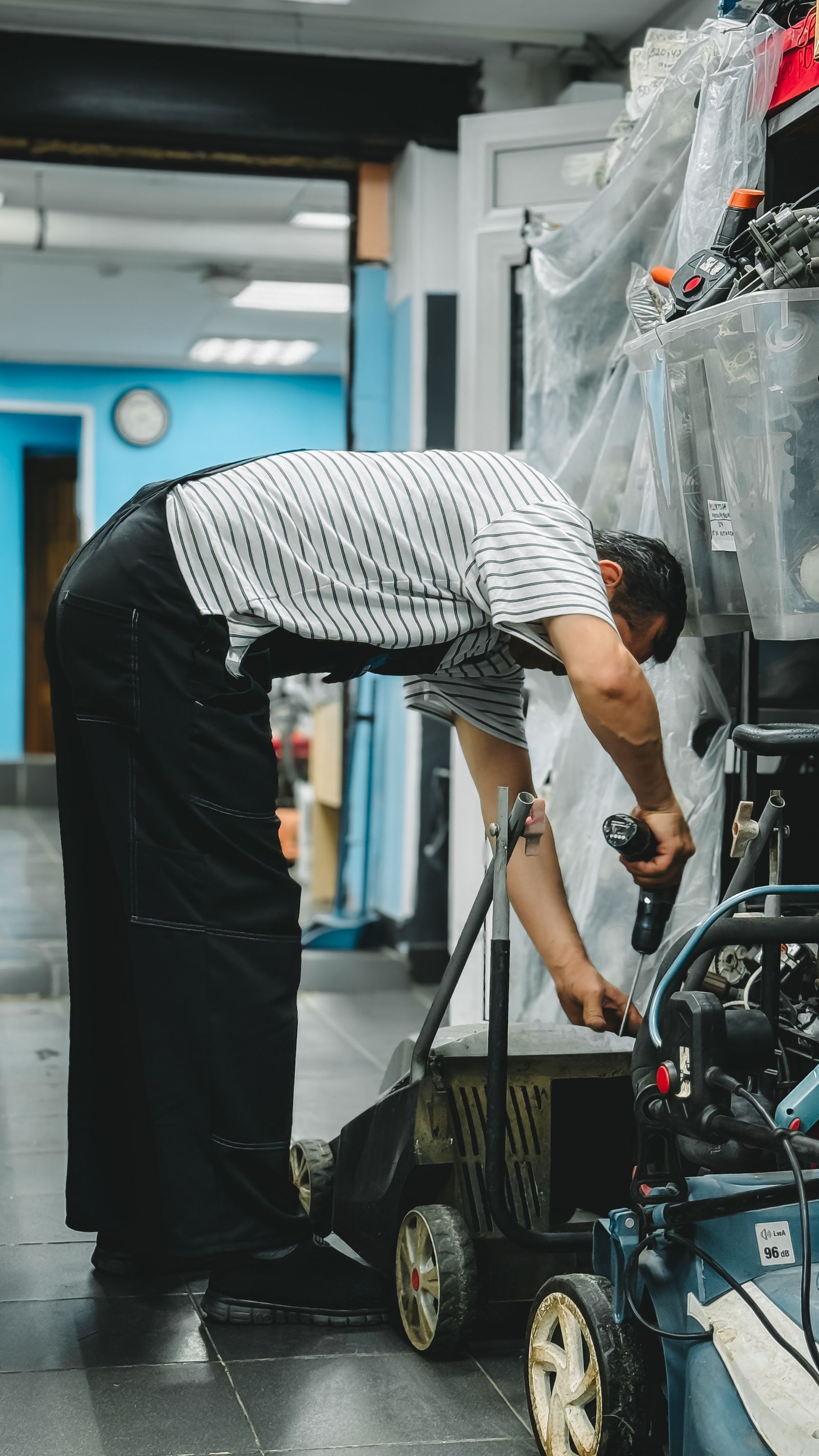 Man repairing lawn mower in workshop