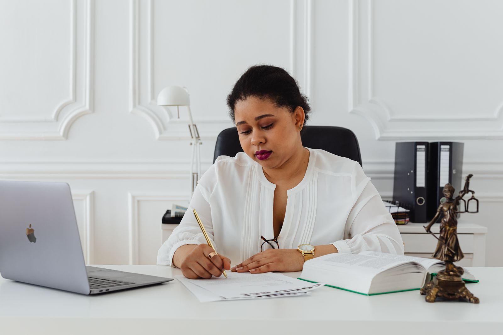 African American woman lawyer signing documents at a desk, symbolizing professionalism