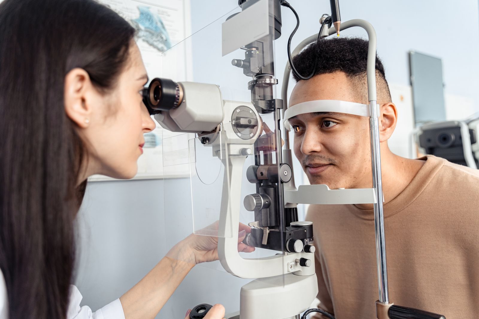 Optometrist examining a patient's eyes with specialized equipment in a clinic setting