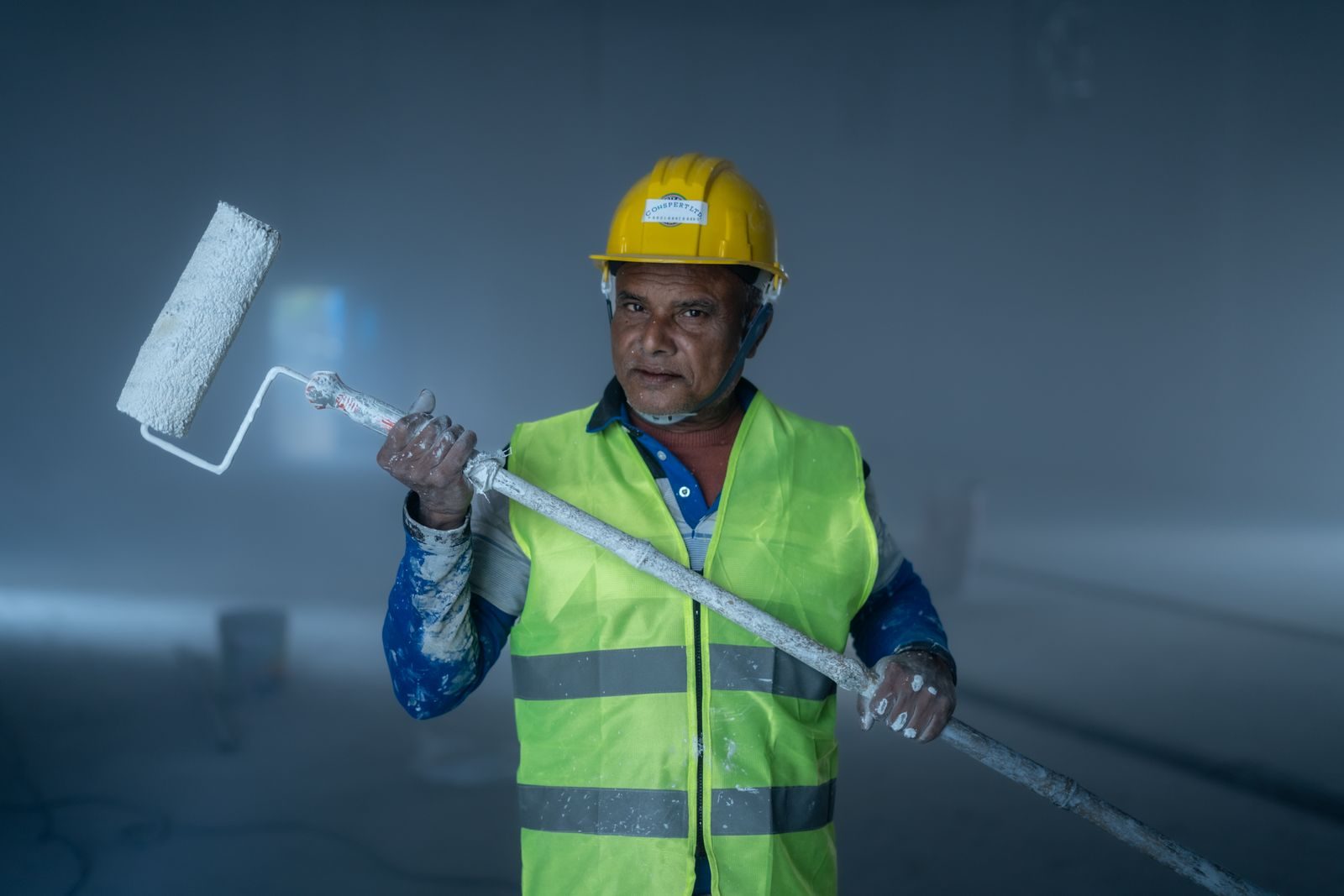 An adult male painter holding a paint roller during a construction project indoors