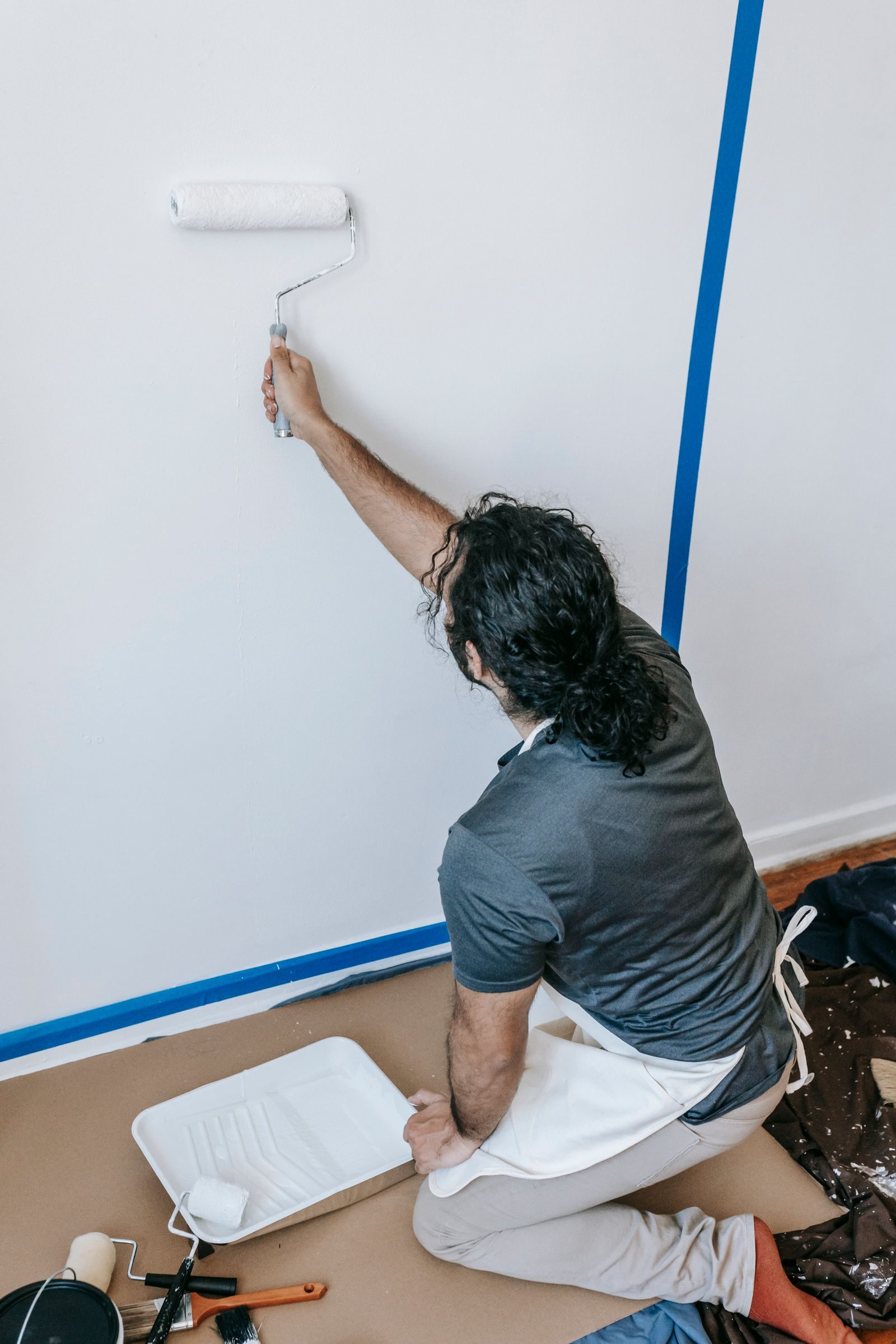Adult man painting a wall with a roller during a home renovation project indoors