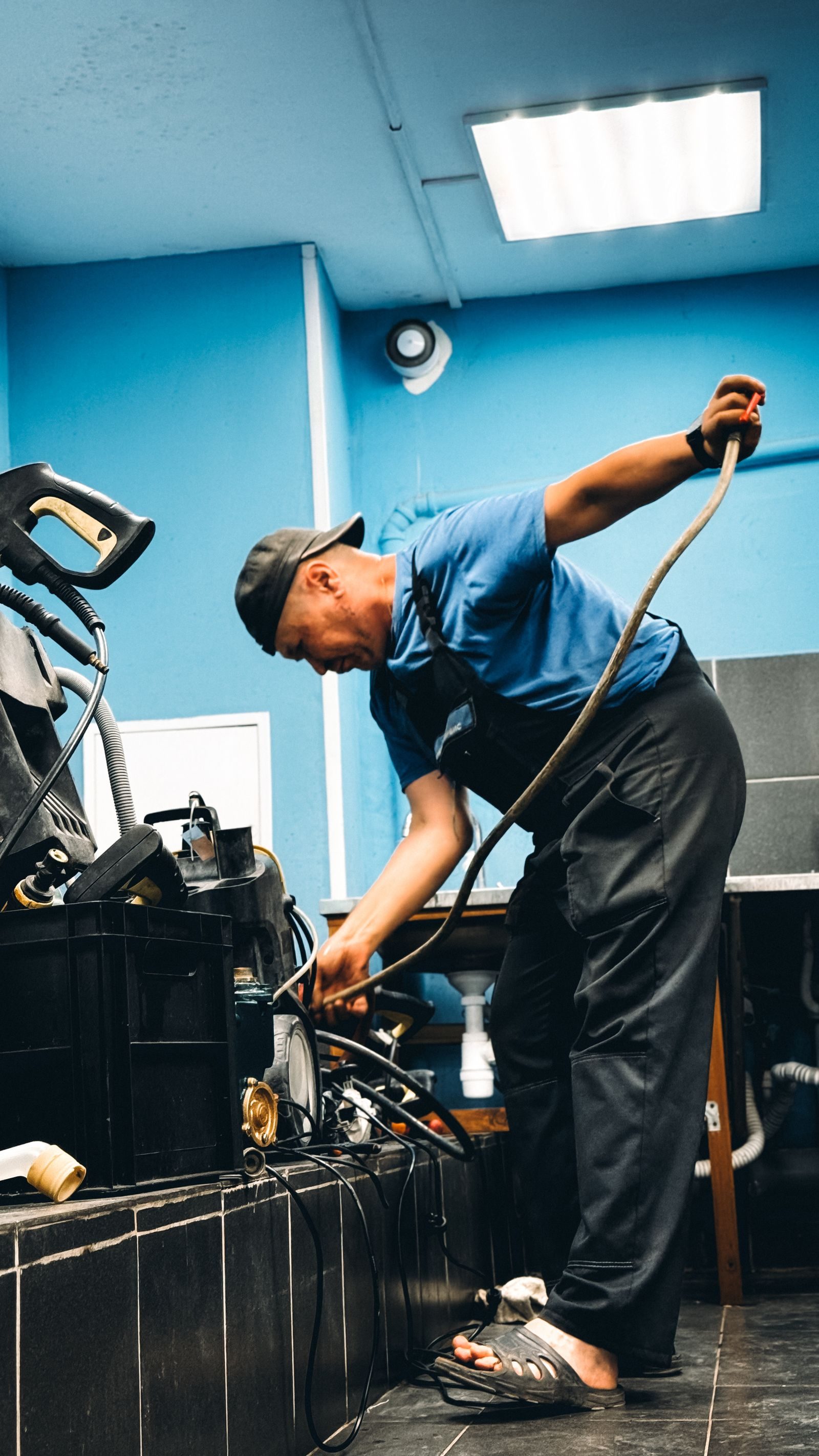 A technician in blue attire repairing equipment in an indoor workshop setting