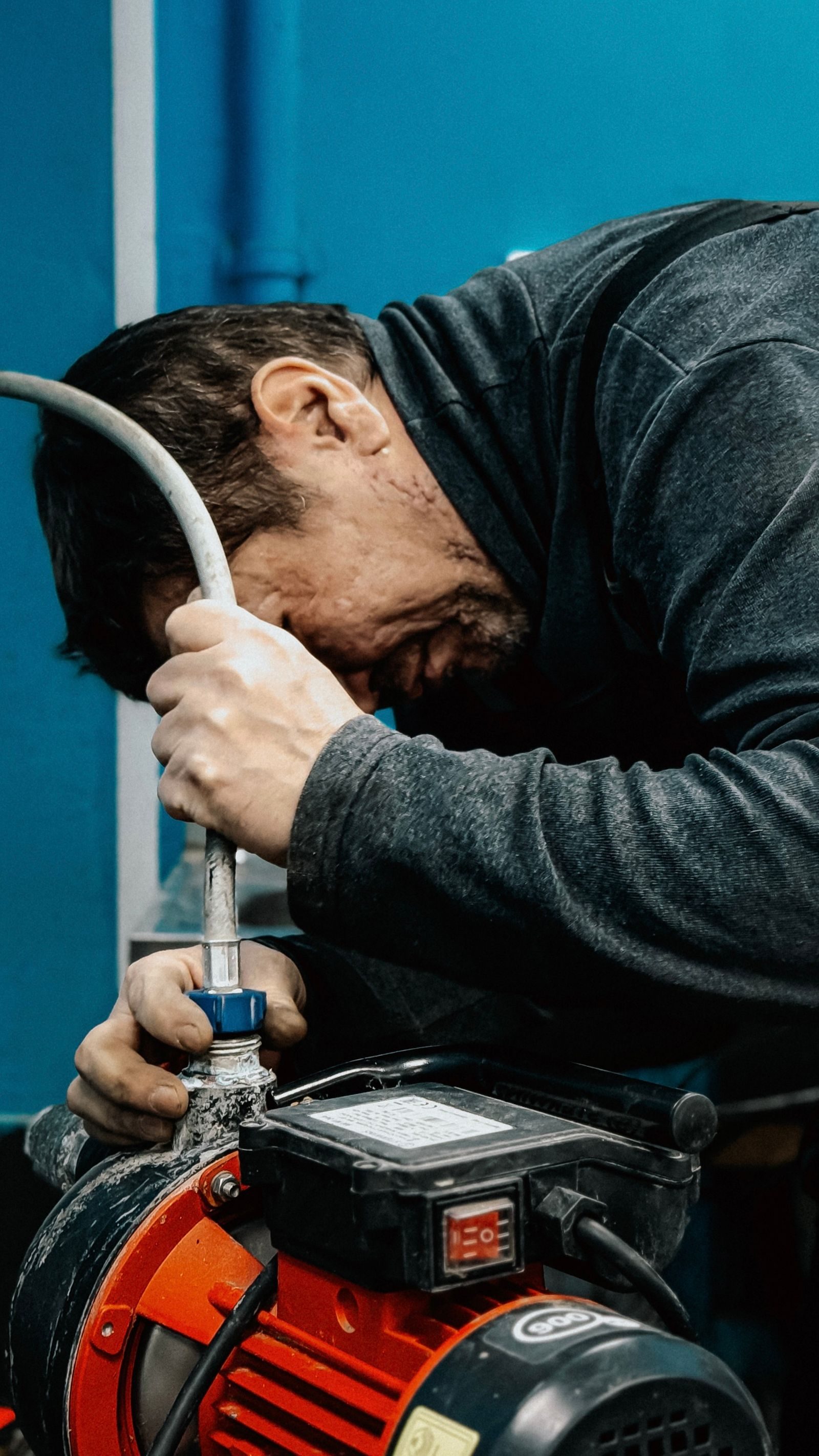 A technician concentrates on adjusting a water pump indoors