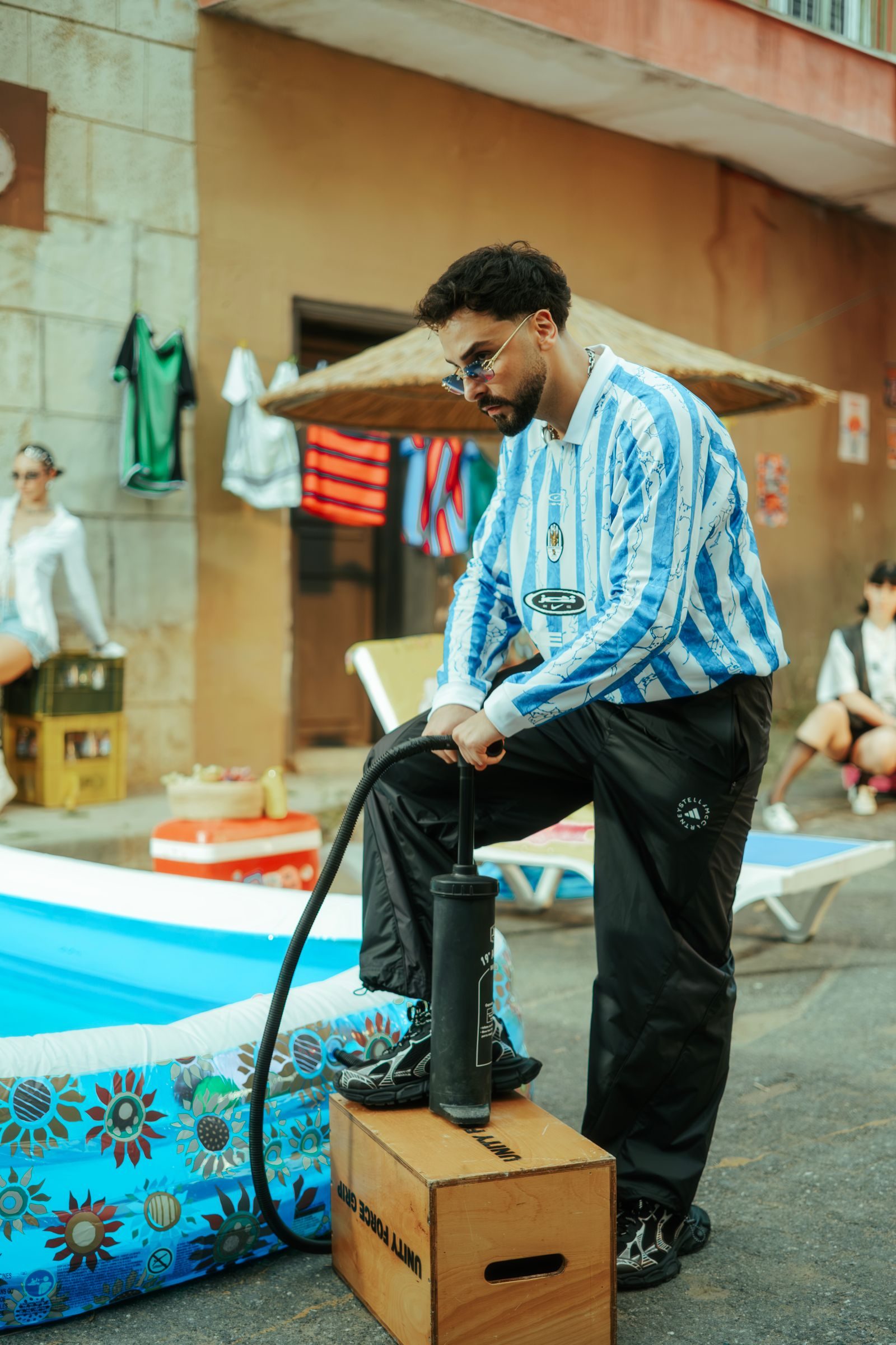 Man inflating pool in vibrant summer street setting, casual atmosphere